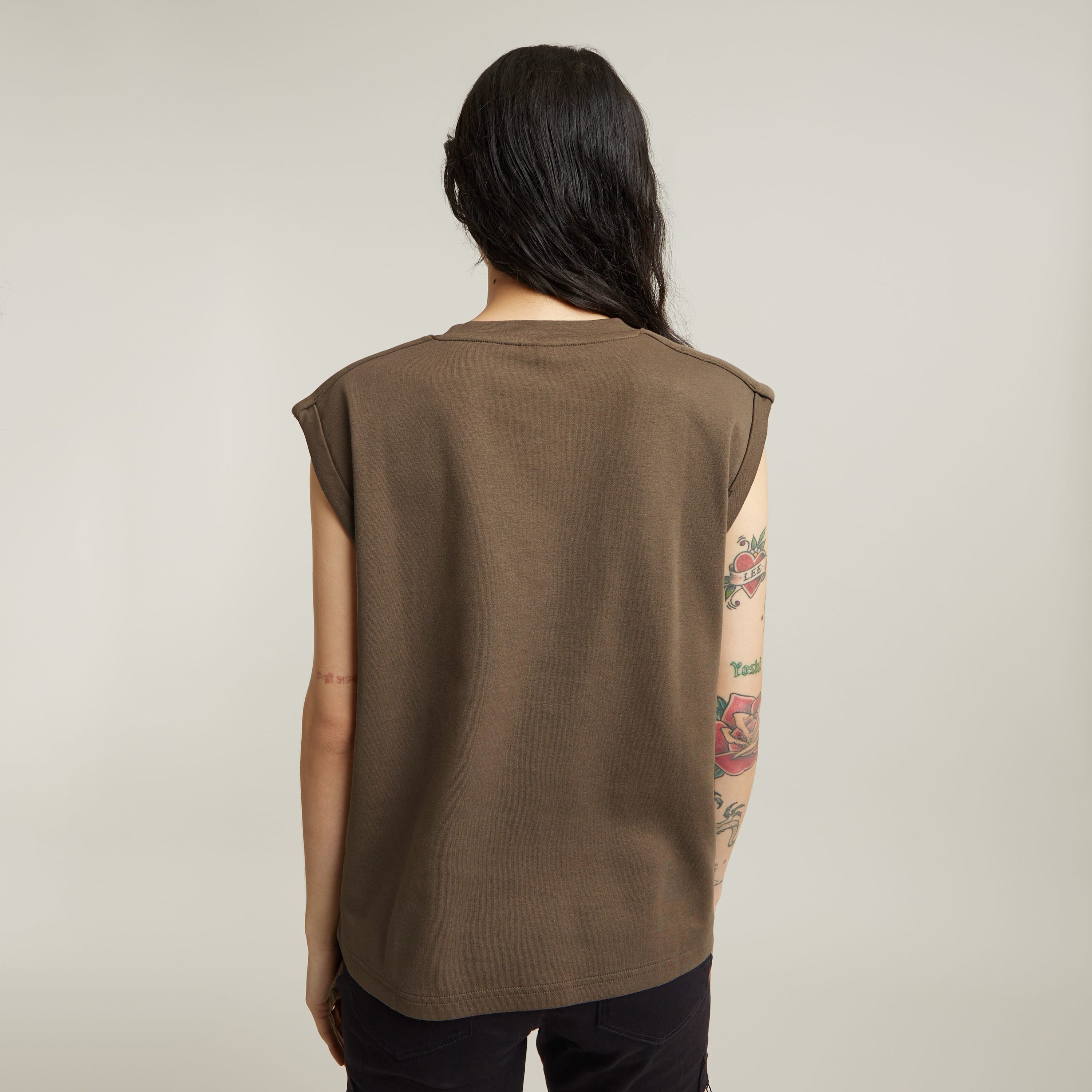 Back view of a woman wearing a constructed loose top with short sleeves in earthy brown.