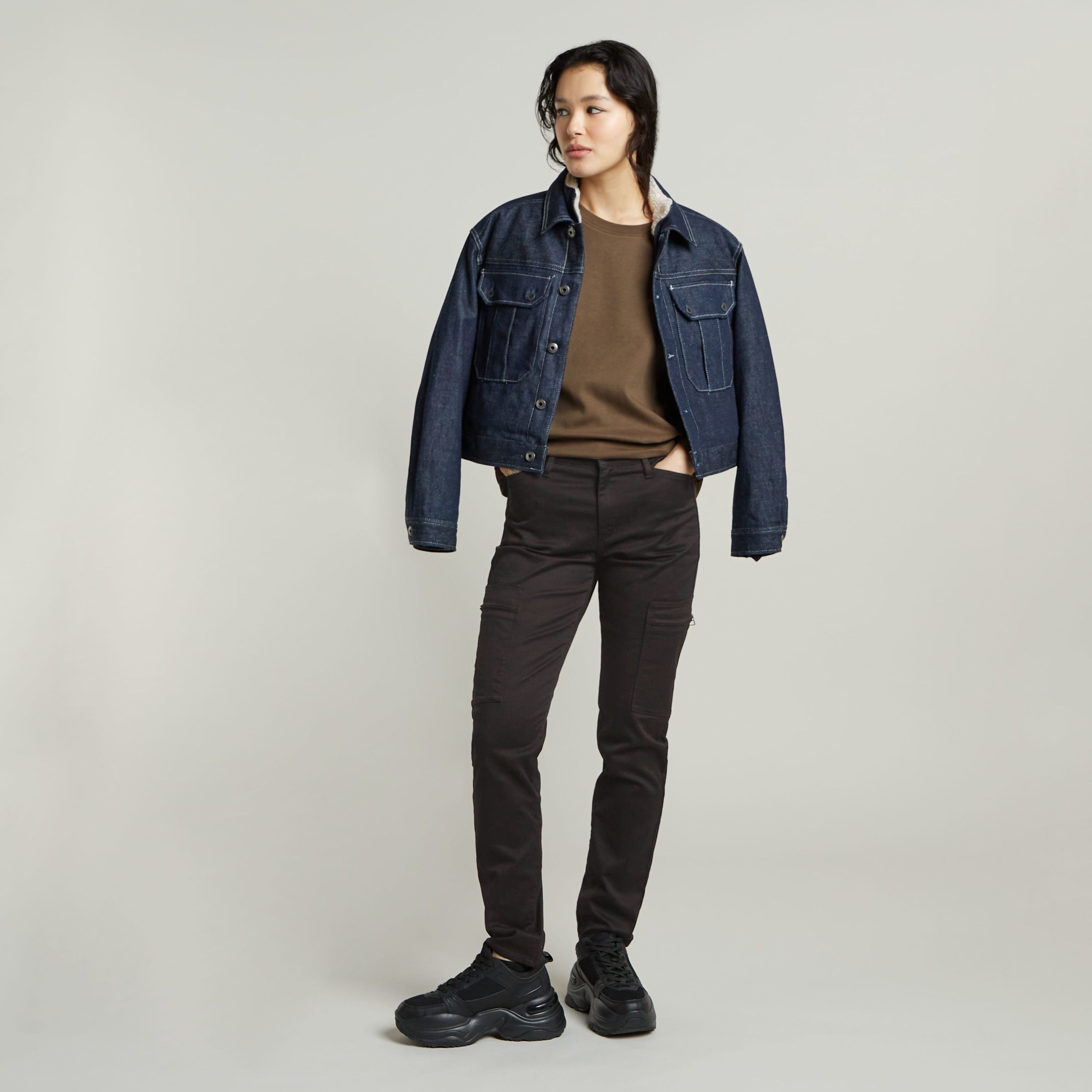Model wearing a constructed loose top with short sleeves, styled with a denim jacket and black pants.