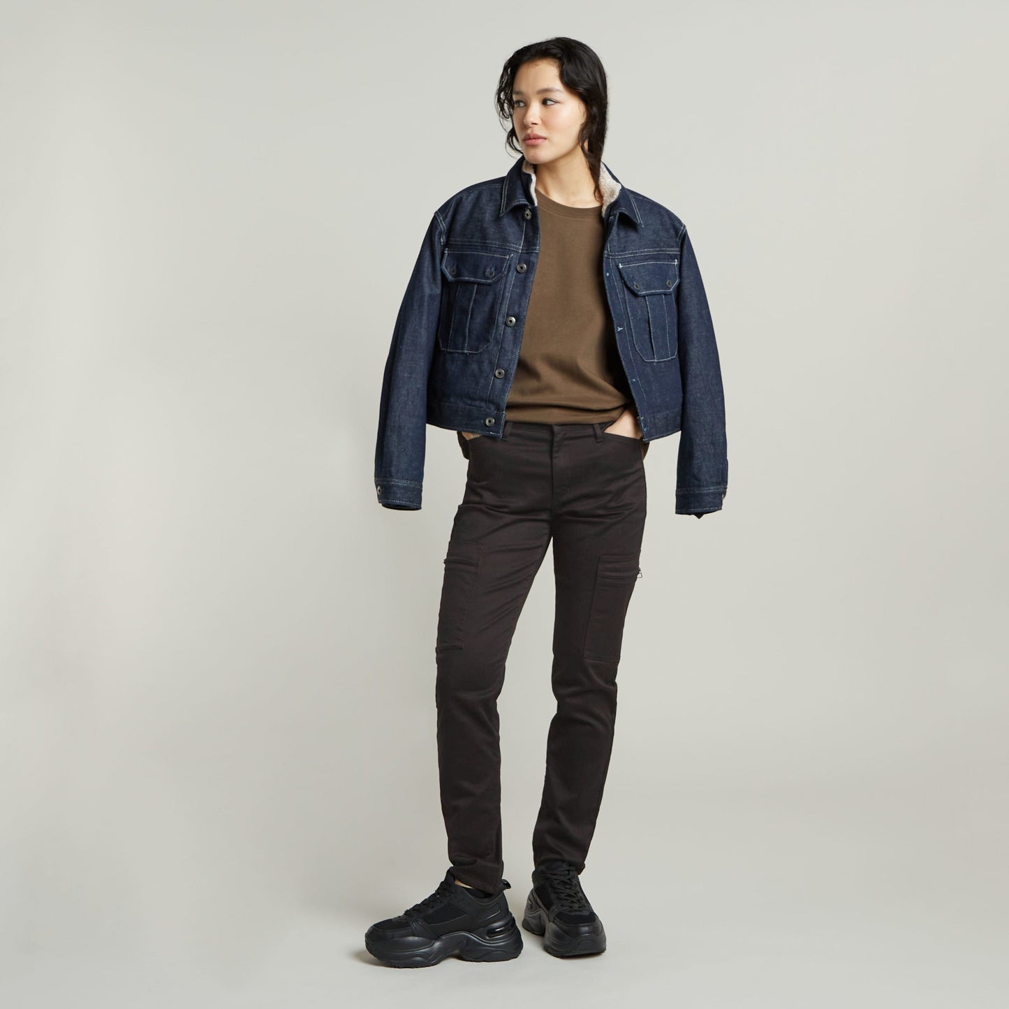 Model wearing a constructed loose top with short sleeves, styled with a denim jacket and black pants.