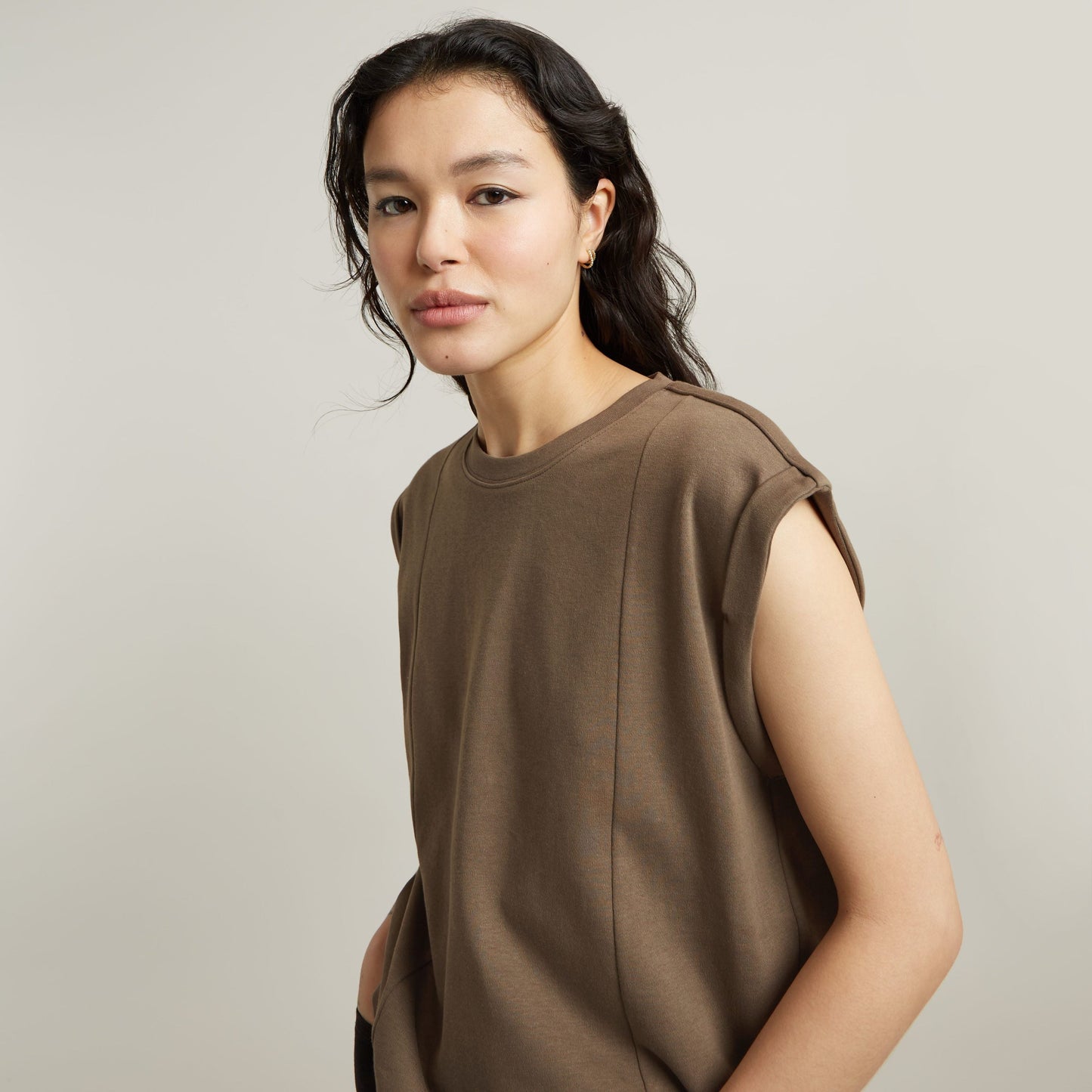constructed loose top with short sleeves in brown worn by a model on a neutral background