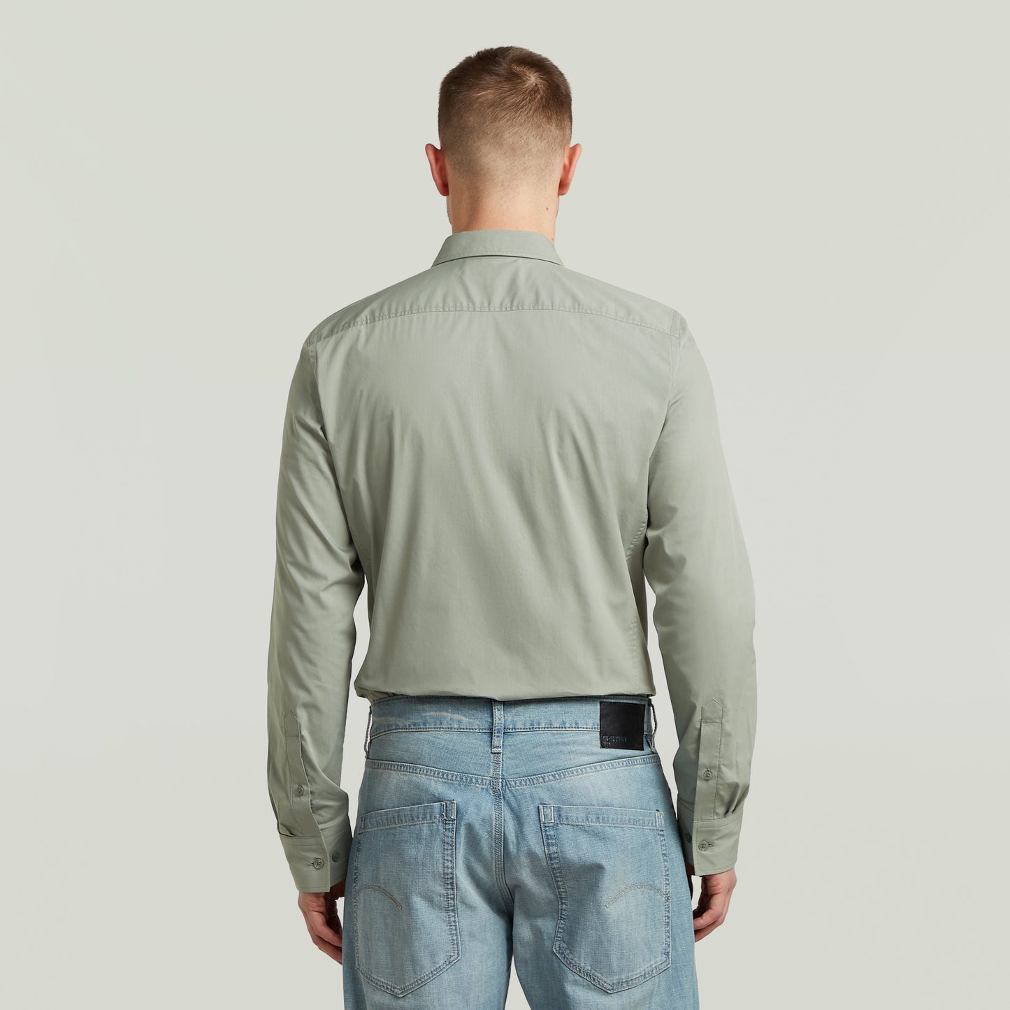Modelo de espaldas vistiendo una camisa uniform slim fit uniform shirt de color verde, vista desde atrás.