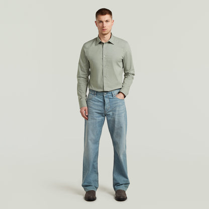 Modelo usando camisa Uniform Slim de manga larga color verde, destacando la slim fit uniform shirt con pantalones de mezclilla.