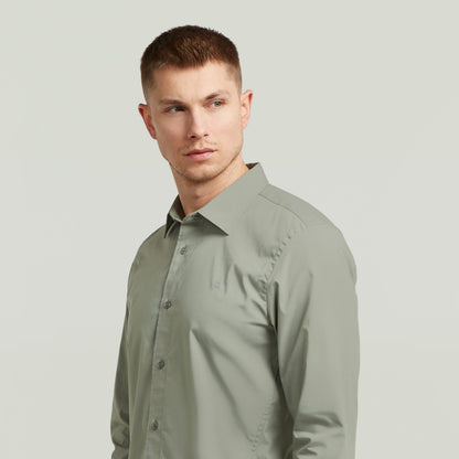 Hombre usando una camisa uniform slim fit uniform shirt de color verde con corte ajustado y cuello de camisa.