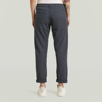 Mujer vista posterior usando los pantalones Kate boyfriend chinos, con perneras ligeramente estrechas y camisetas.