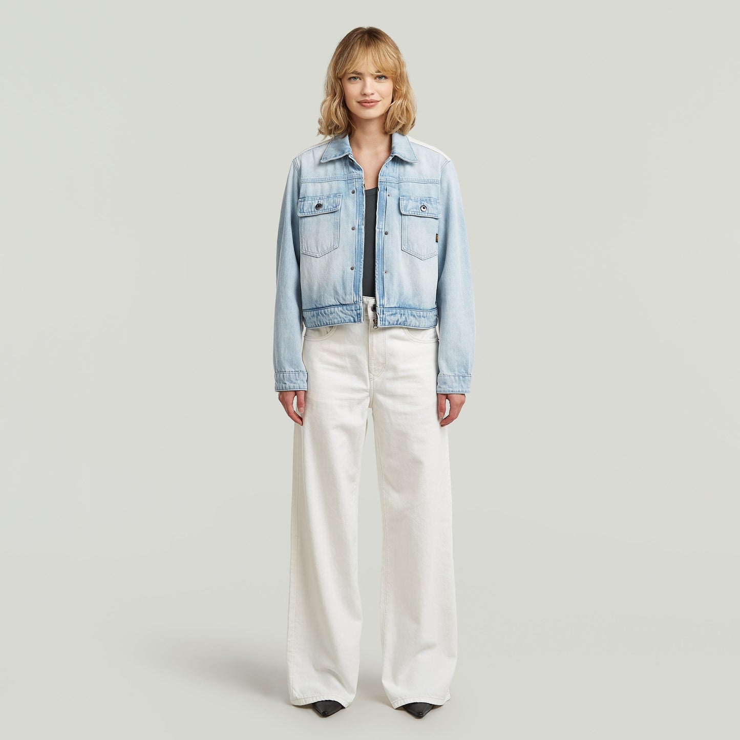 Model wearing high loose skater jeans with a cropped denim jacket, showcasing street style fashion.