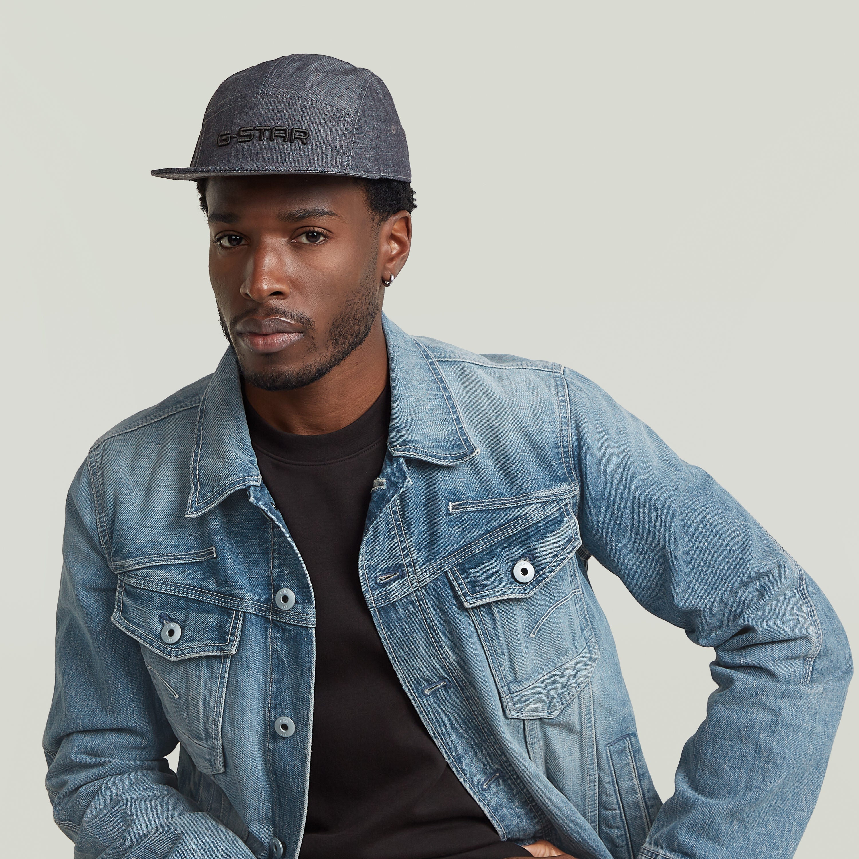 Hombre luciendo la gorra Flat Brim 5 Panel de G-STAR con chaqueta de mezclilla.