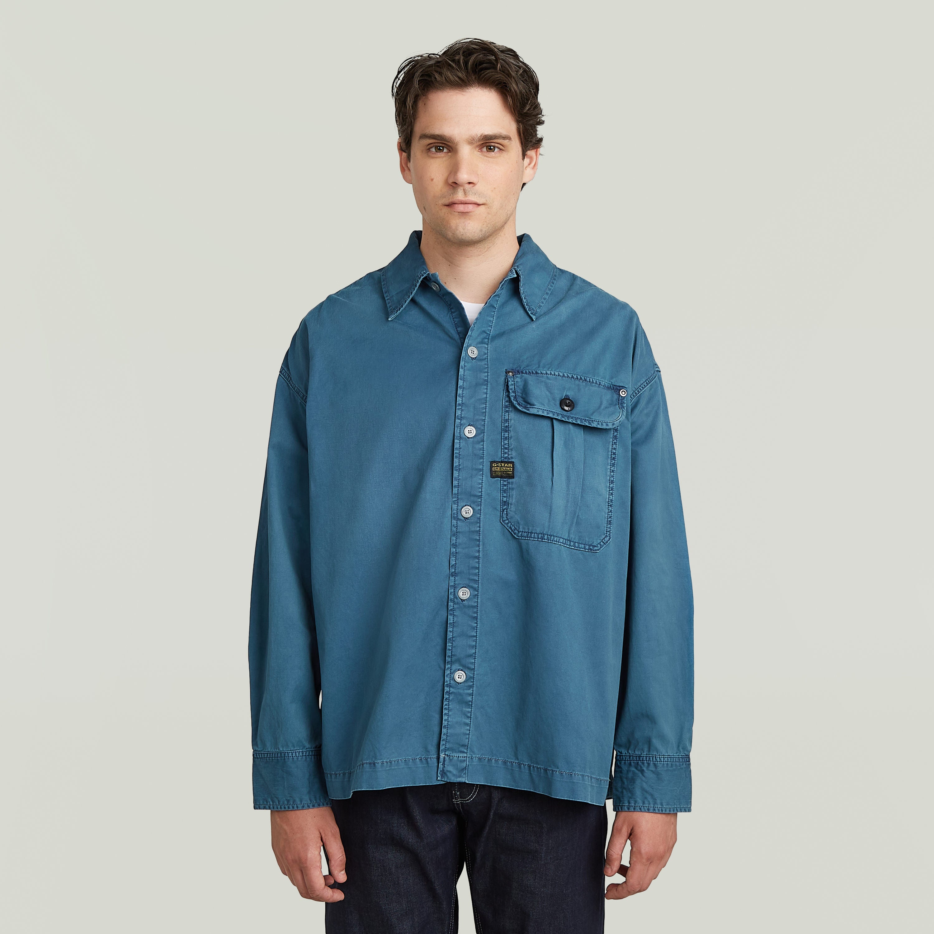 boxy pleated shirt with pocket in blue, featuring a relaxed oversized fit and chest pocket