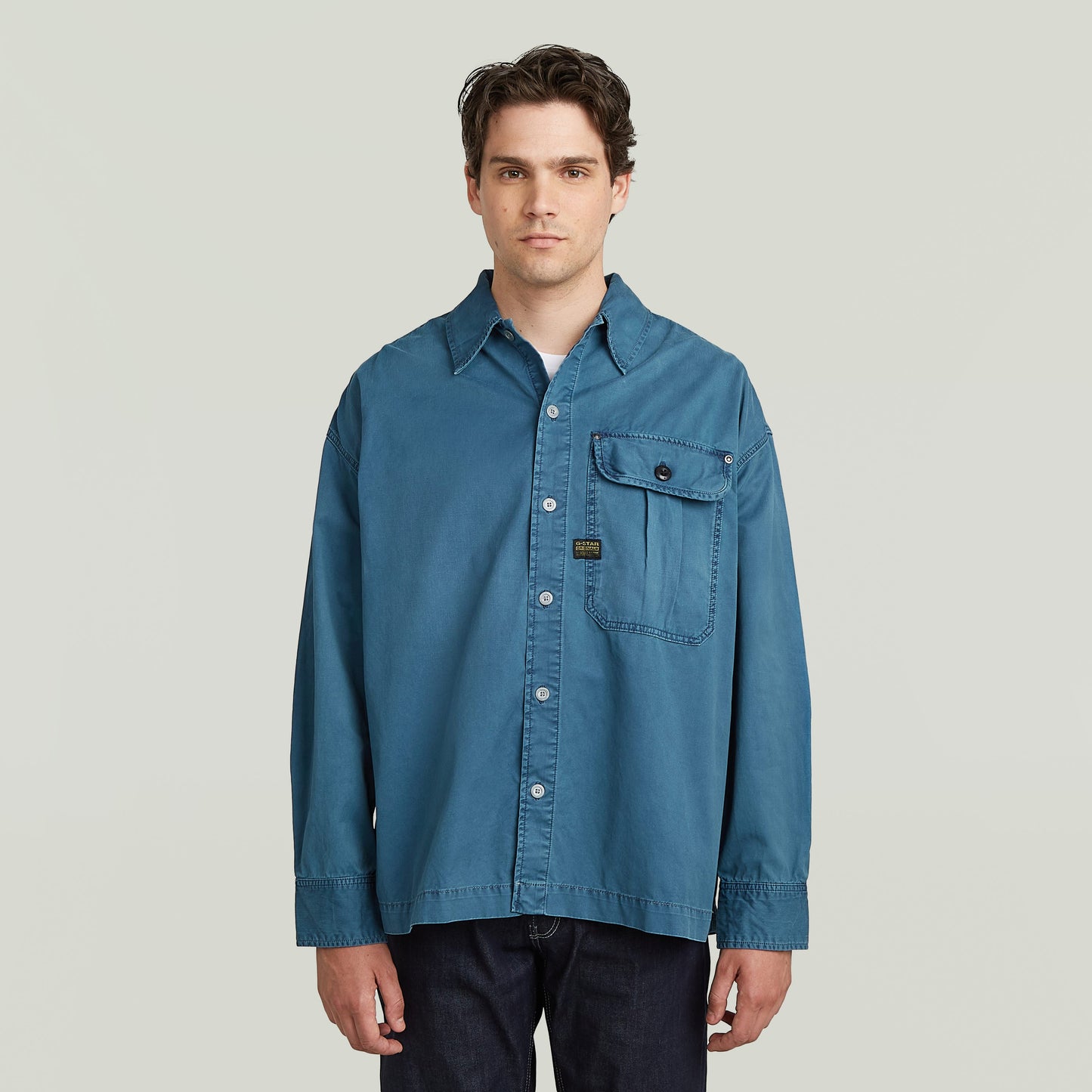 boxy pleated shirt with pocket in blue, featuring a relaxed oversized fit and chest pocket