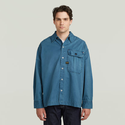 boxy pleated shirt with pocket in blue, featuring a relaxed oversized fit and chest pocket