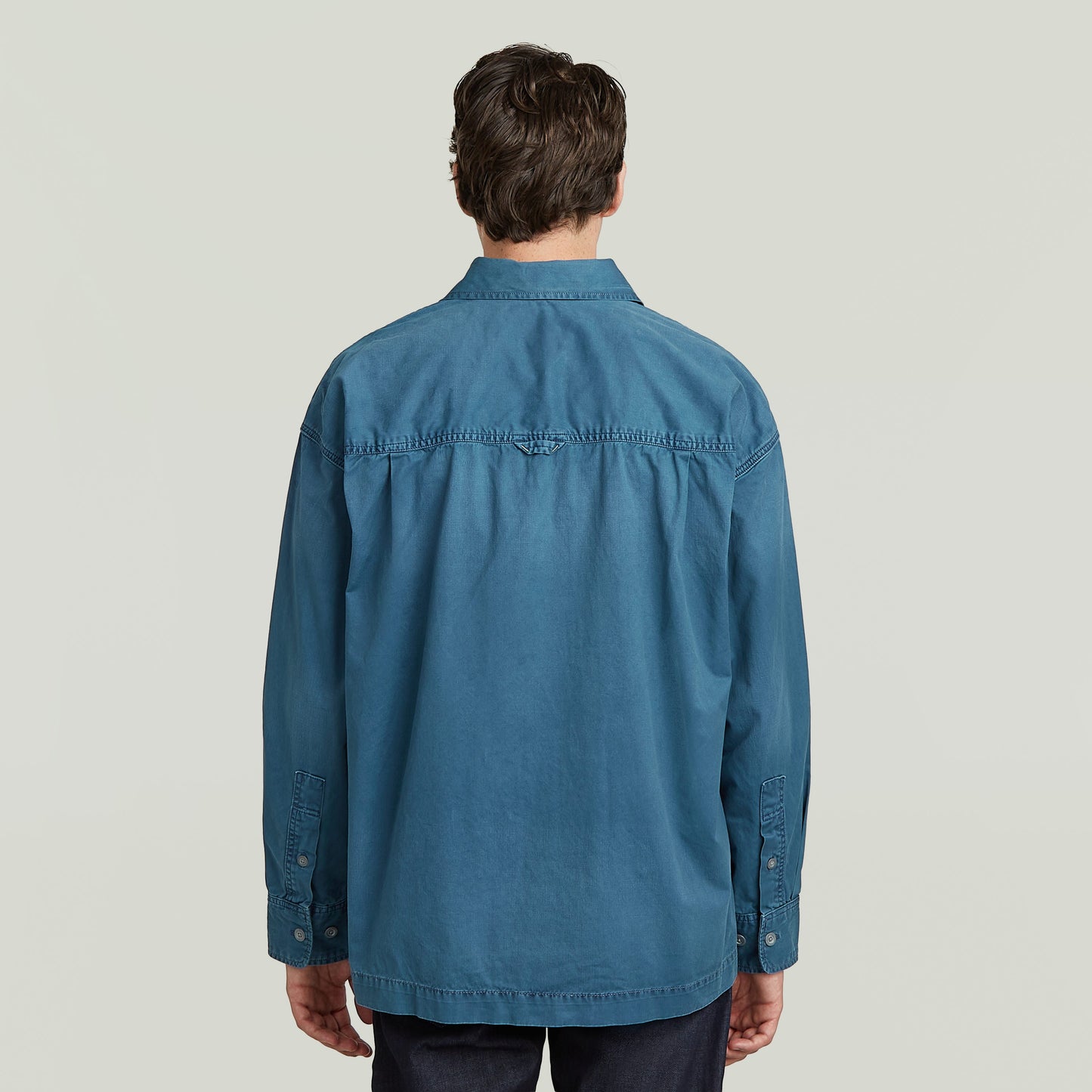 Hombre de espaldas vistiendo una camisa plisada 1 Pocket Boxy en color azul, vista trasera.
