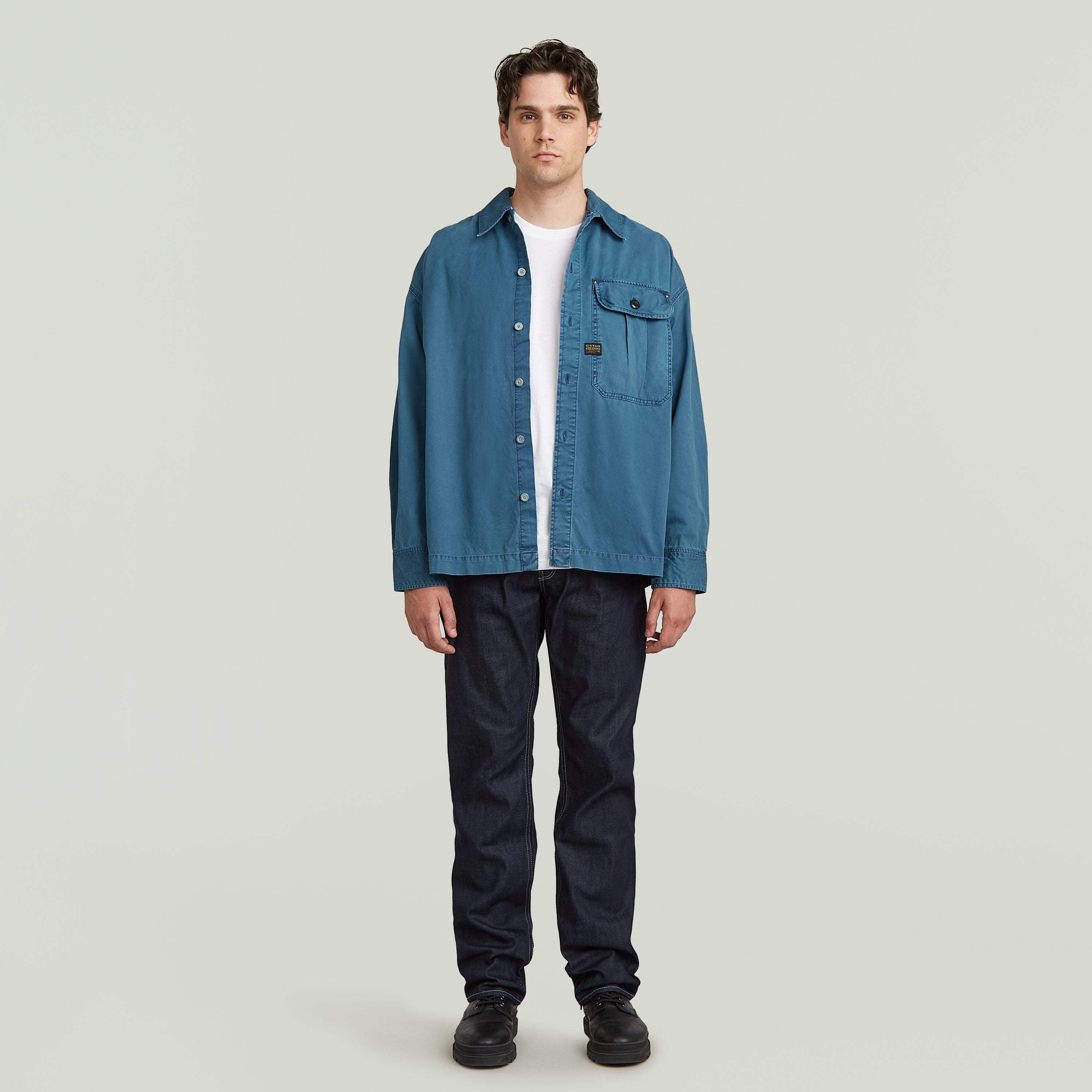 boxy pleated shirt with pocket in blue worn by a model, featuring a relaxed oversized fit and chest pocket.