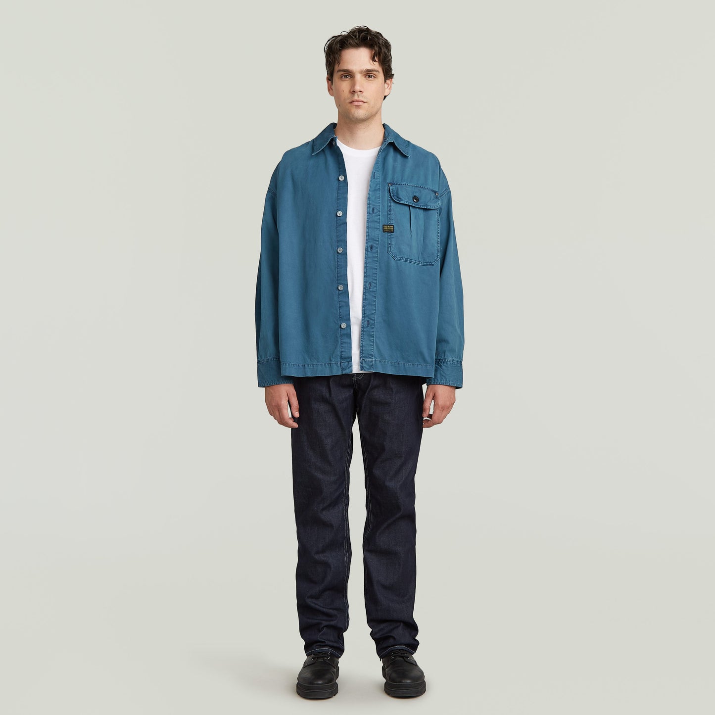 boxy pleated shirt with pocket in blue worn by a model, featuring a relaxed oversized fit and chest pocket.
