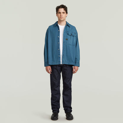 boxy pleated shirt with pocket in blue worn by a model, featuring a relaxed oversized fit and chest pocket.