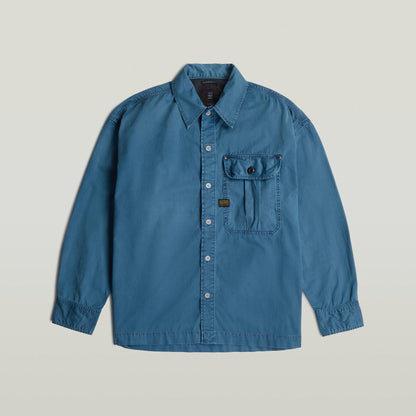 Camisa plisada 1 Pocket Boxy, una boxy pleated shirt with pocket en color azul, corte relajado y detalles de diseño.