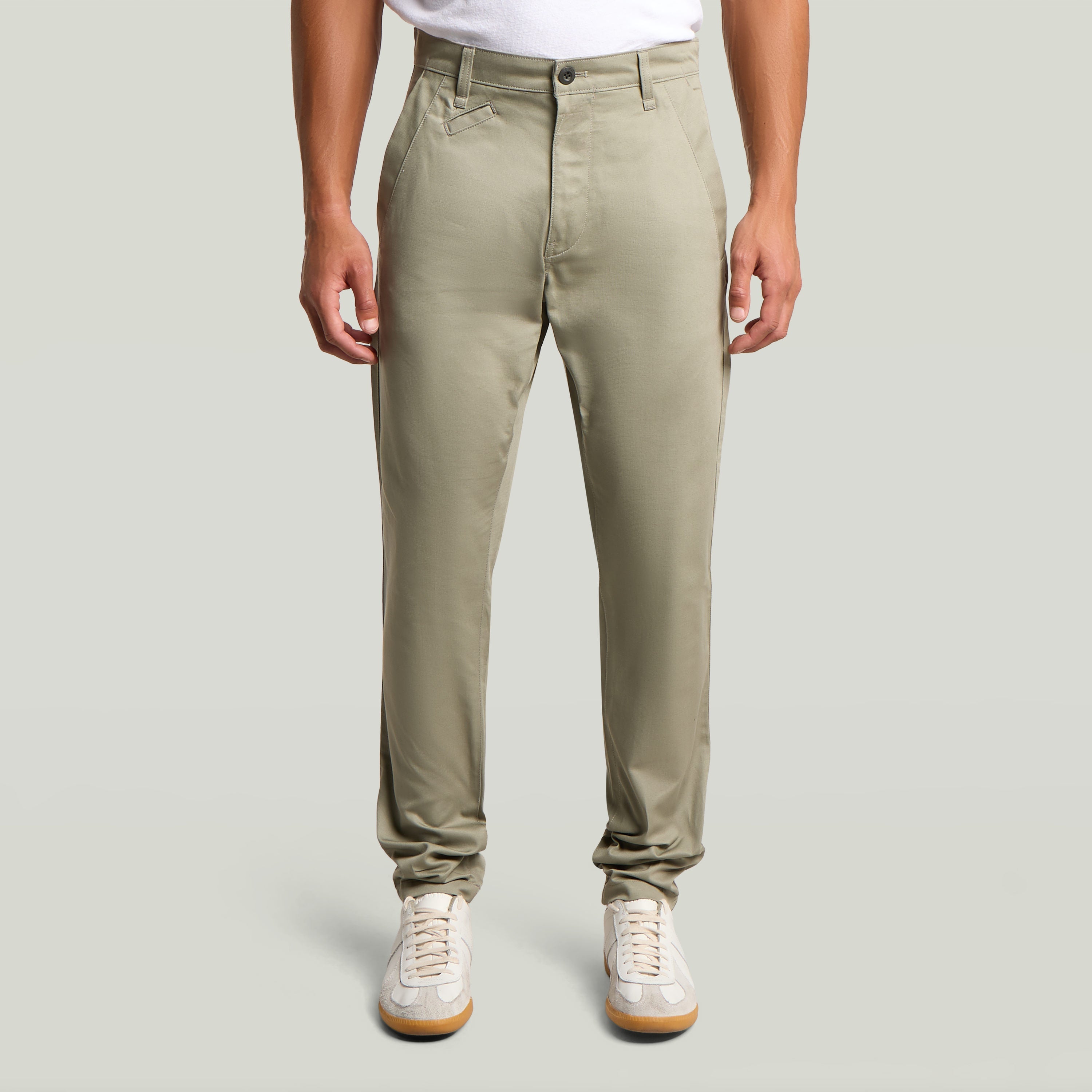Modelo usando pantalones Bronson 3.0 slim fit chino en color verde claro con camiseta blanca y zapatillas.