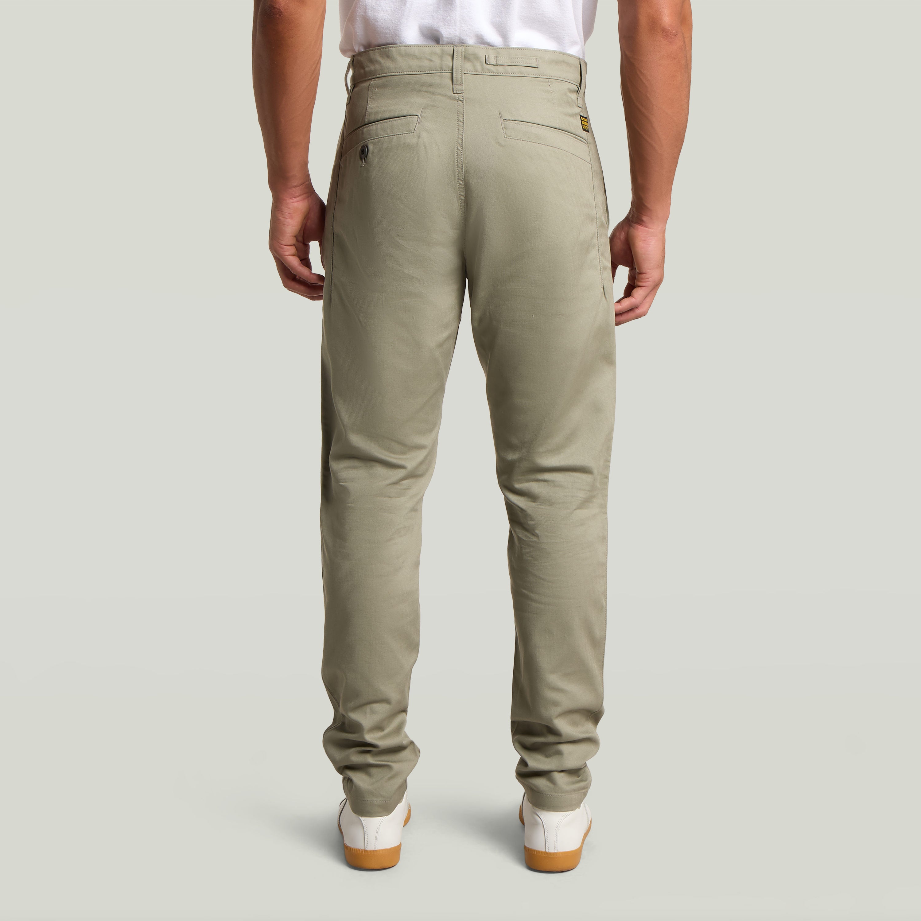Pantalones Bronson 3.0 Slim Chino, vistos desde atrás, en color verde claro, con detalles de diseño y ajuste moderno.