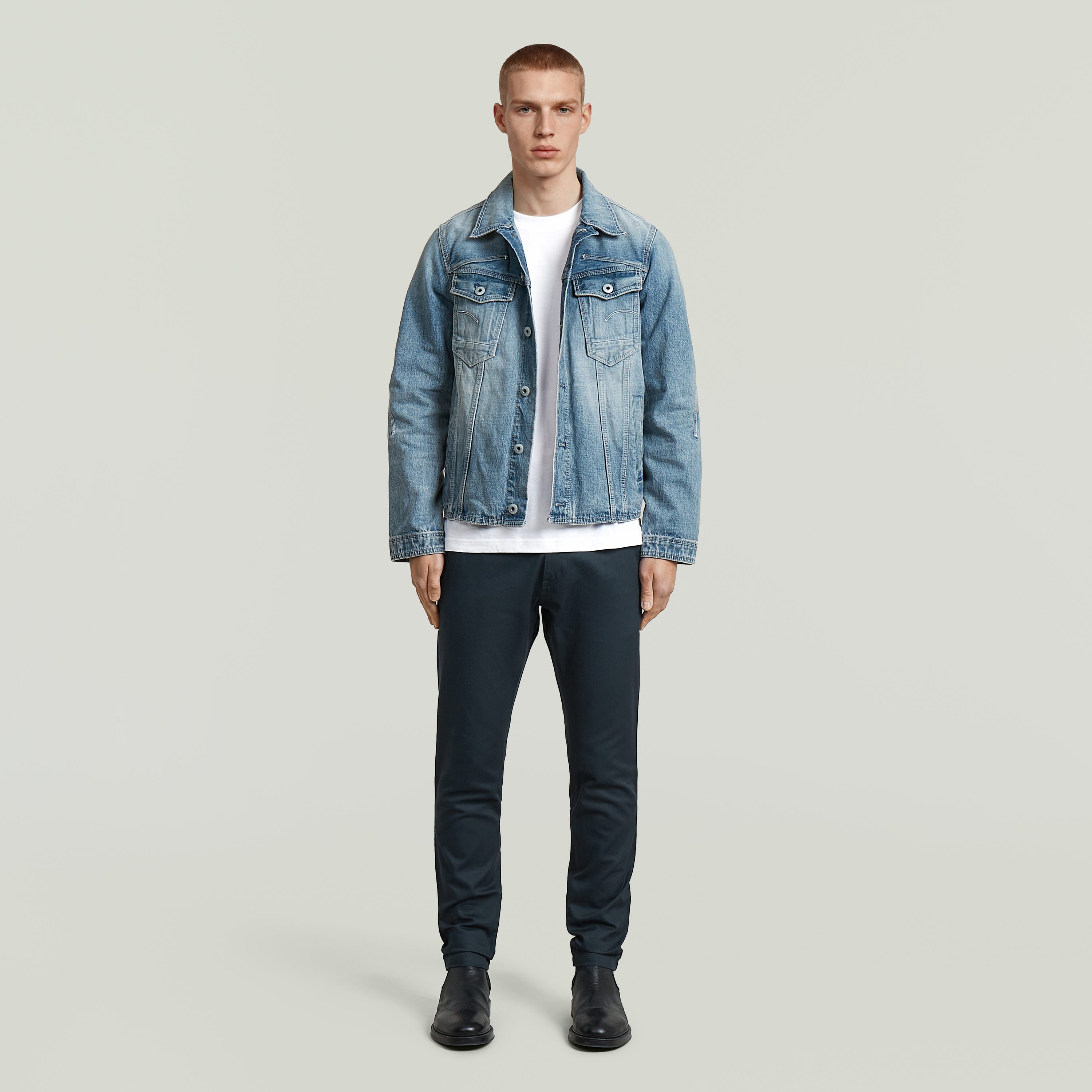 Modelo masculino vistiendo chaqueta de mezclilla con camiseta blanca y pantalones Bronson 3.0 slim chino pants.