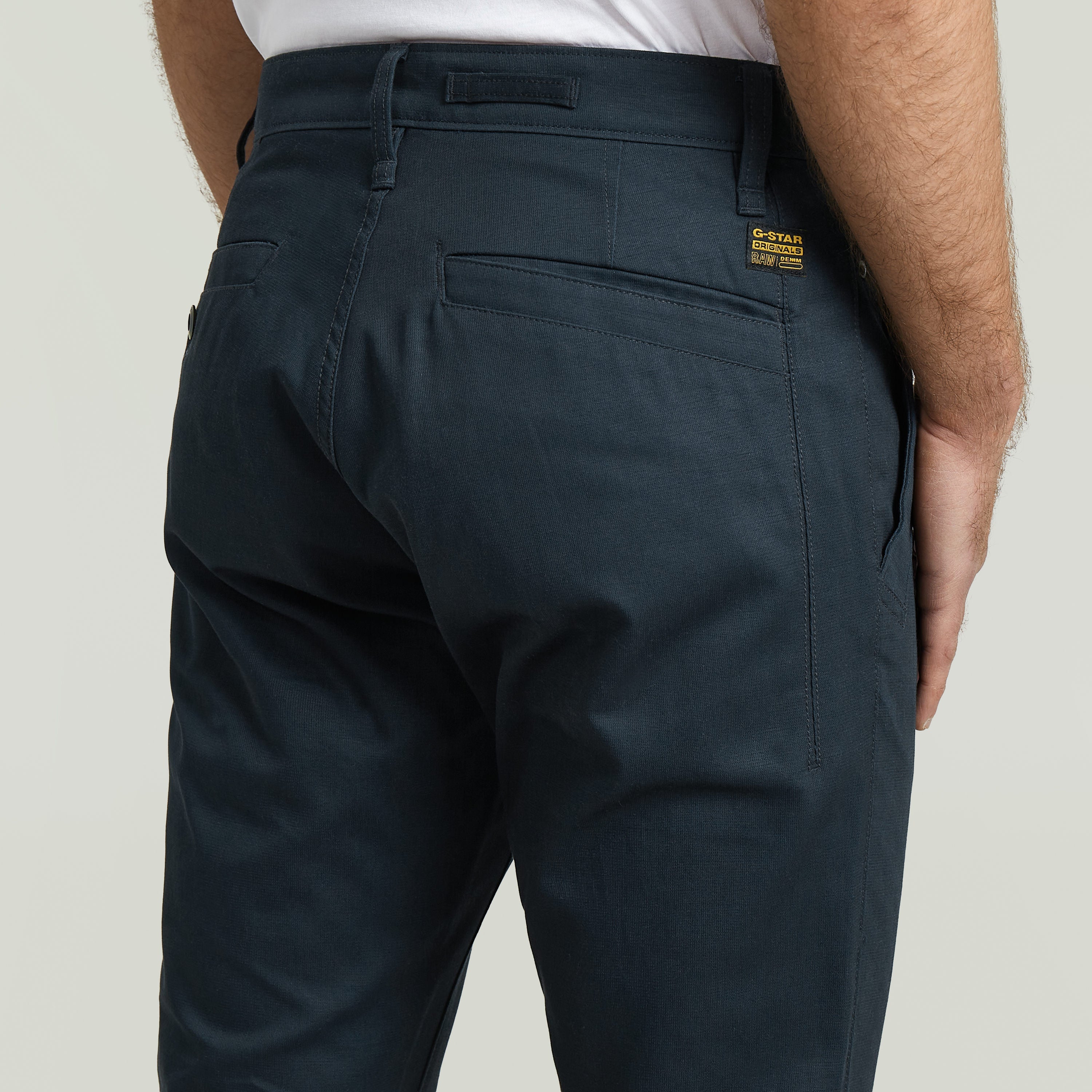 Modelo usando Pantalones Bronson 3.0 Slim Chino, vista posterior con detalles de costura y bolsillos.