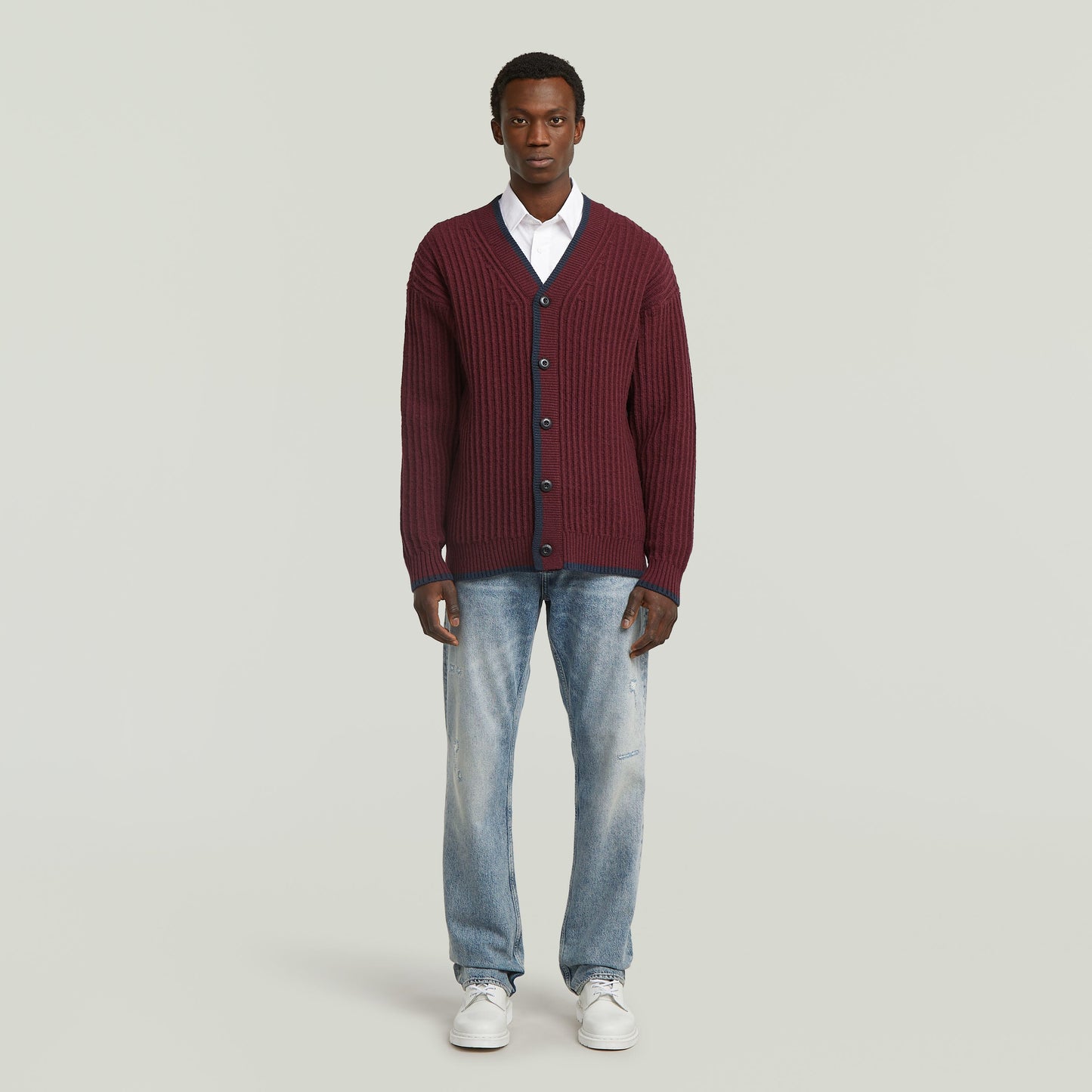 men's V-neck cardigan knit worn by a model in burgundy color with a casual outfit.