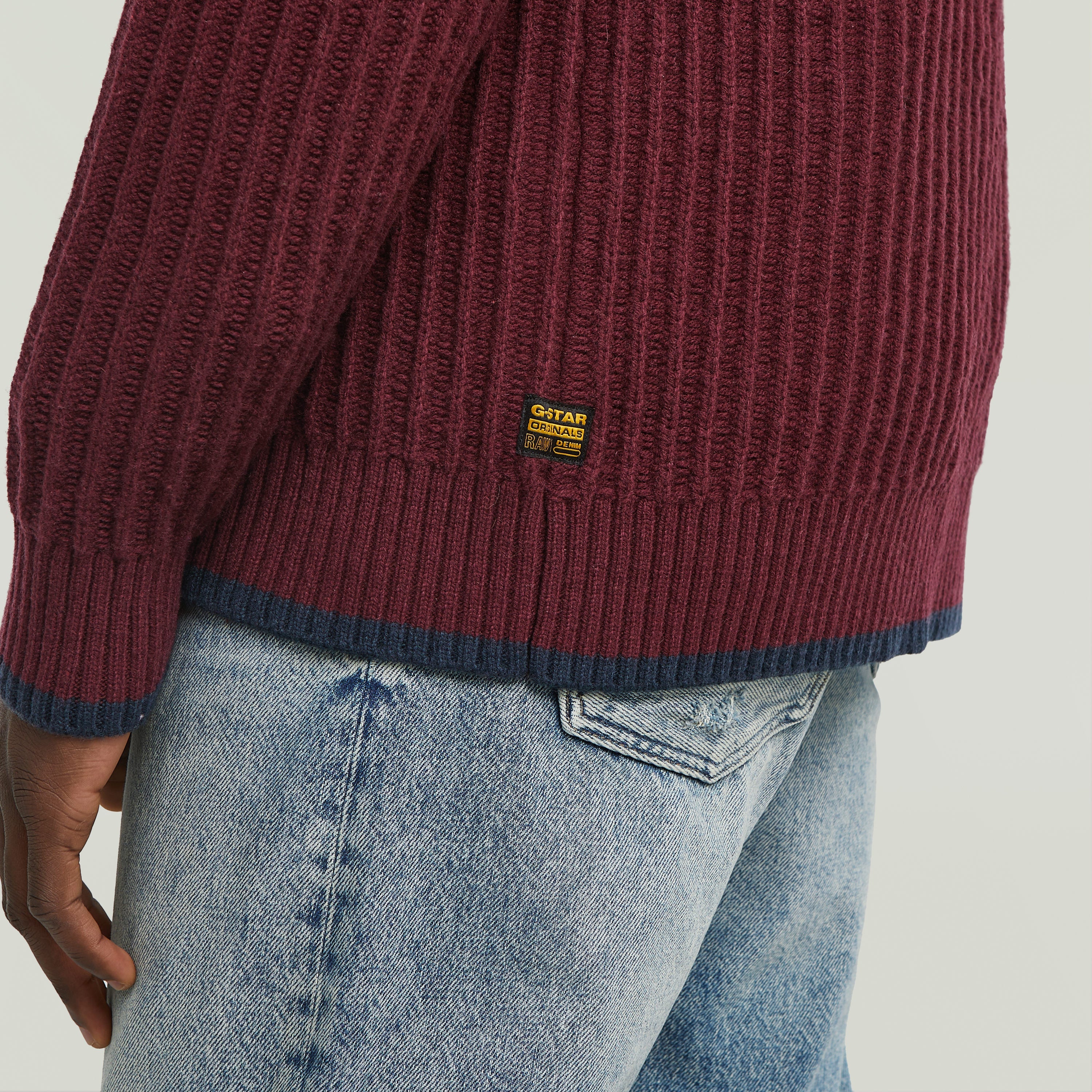 men's V-neck cardigan knit showing ribbed texture and label detail on the back.