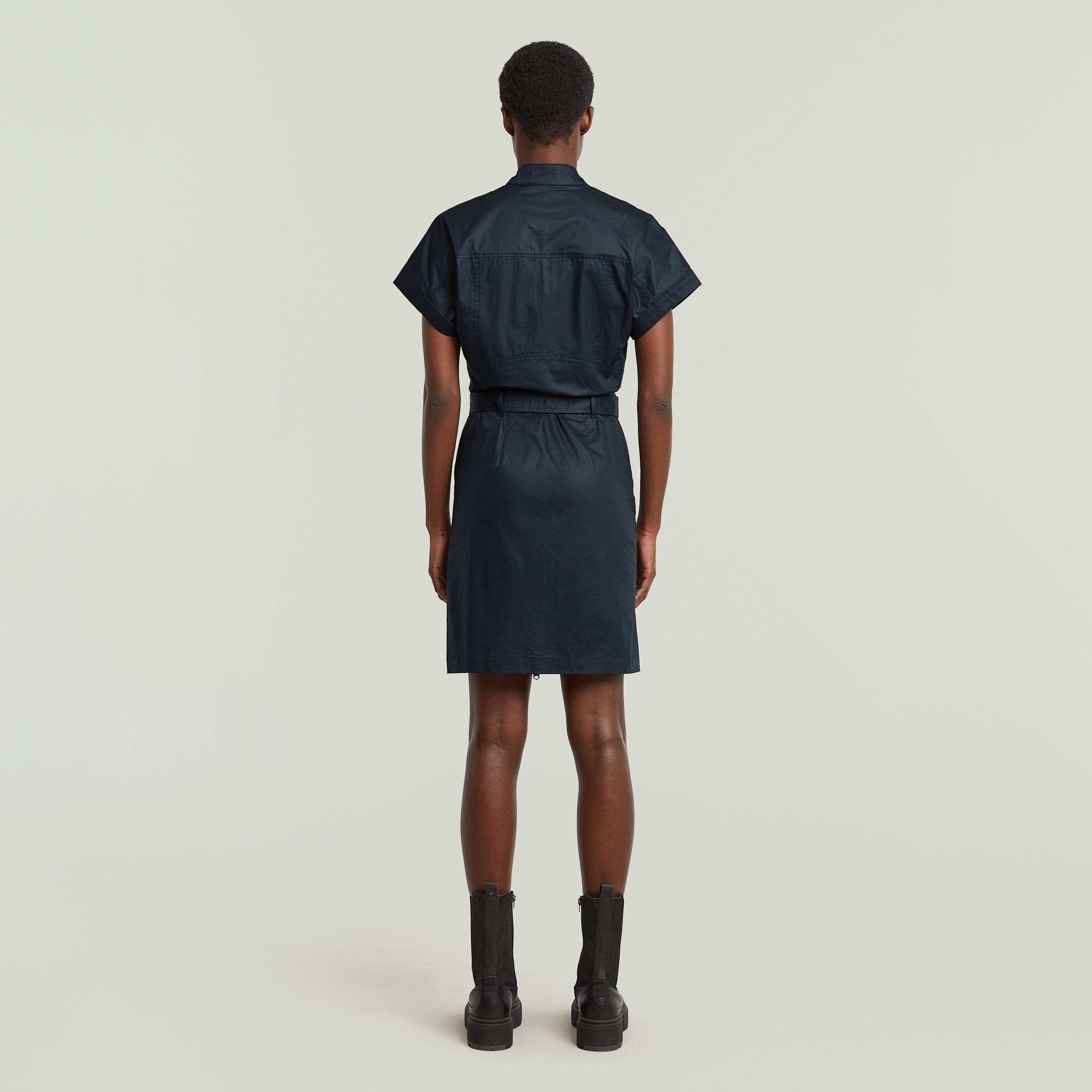 Mujer de espaldas luciendo vestido belted de algodón orgánico color azul oscuro.