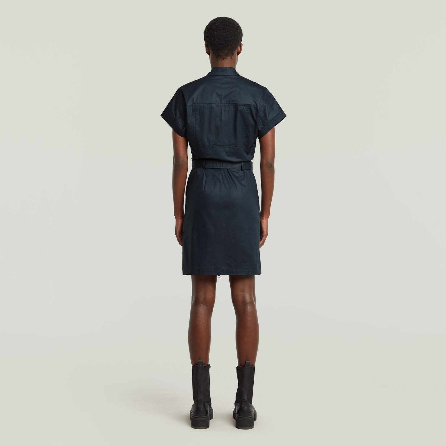 Mujer de espaldas luciendo vestido belted de algodón orgánico color azul oscuro.