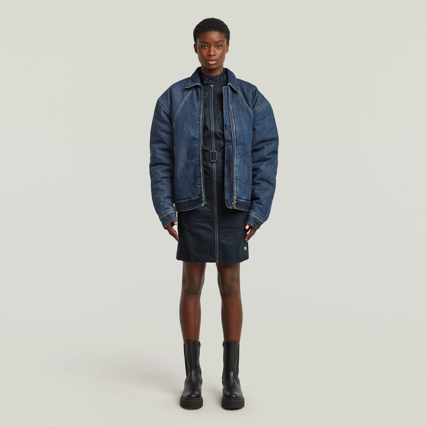 Model wearing a dark blue organic cotton belted dress with an oversized denim jacket and black boots.