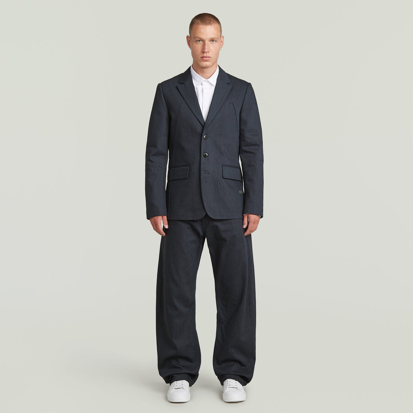 A-Line tailored denim blazer worn by a man, featuring structured silhouette and classic button closure in dark blue.
