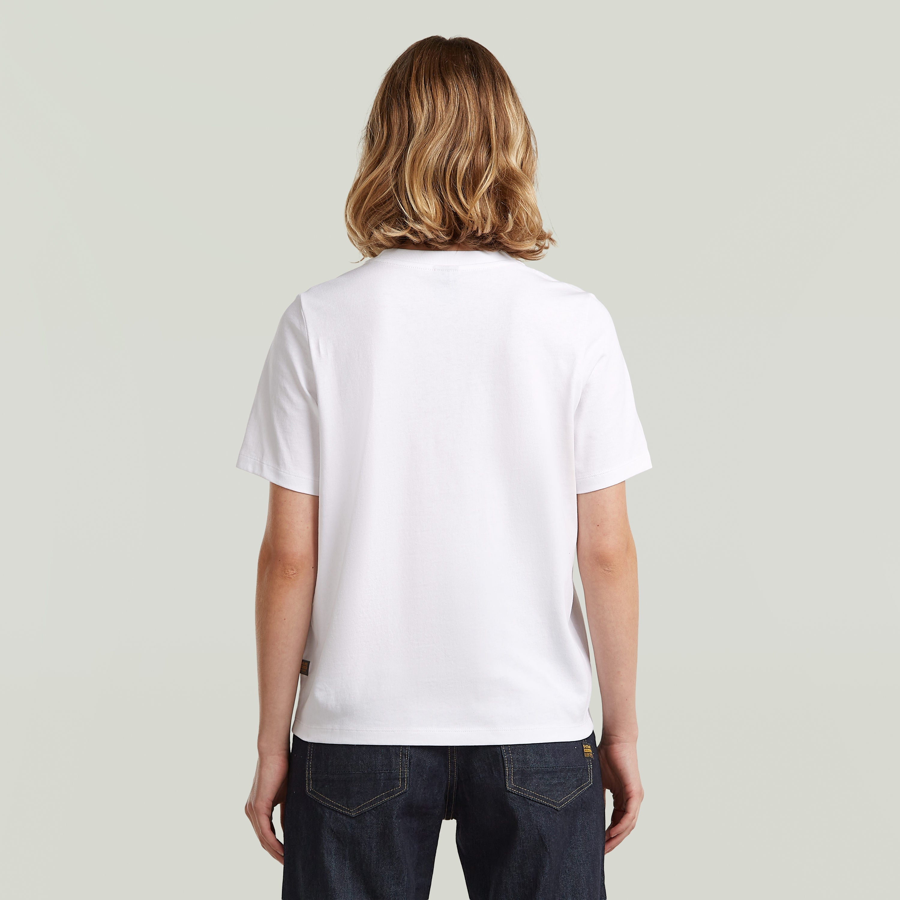 Parte posterior de una camiseta gráfica de algodón ecológico color blanco, con corte recto y manga corta.