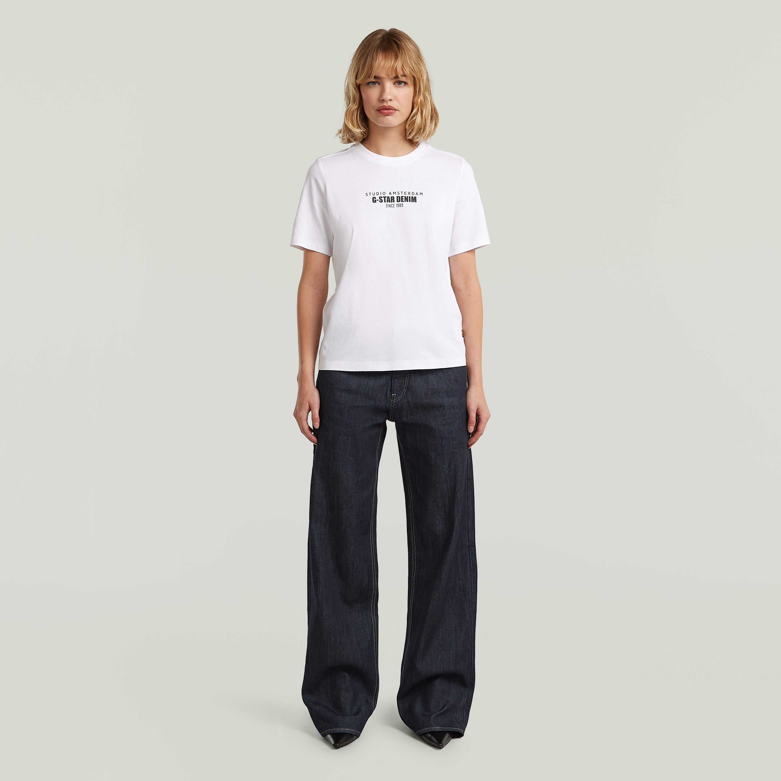 Camiseta gráfica de algodón ecológico blanca con estampado, usada por modelo con pantalones oscuros.