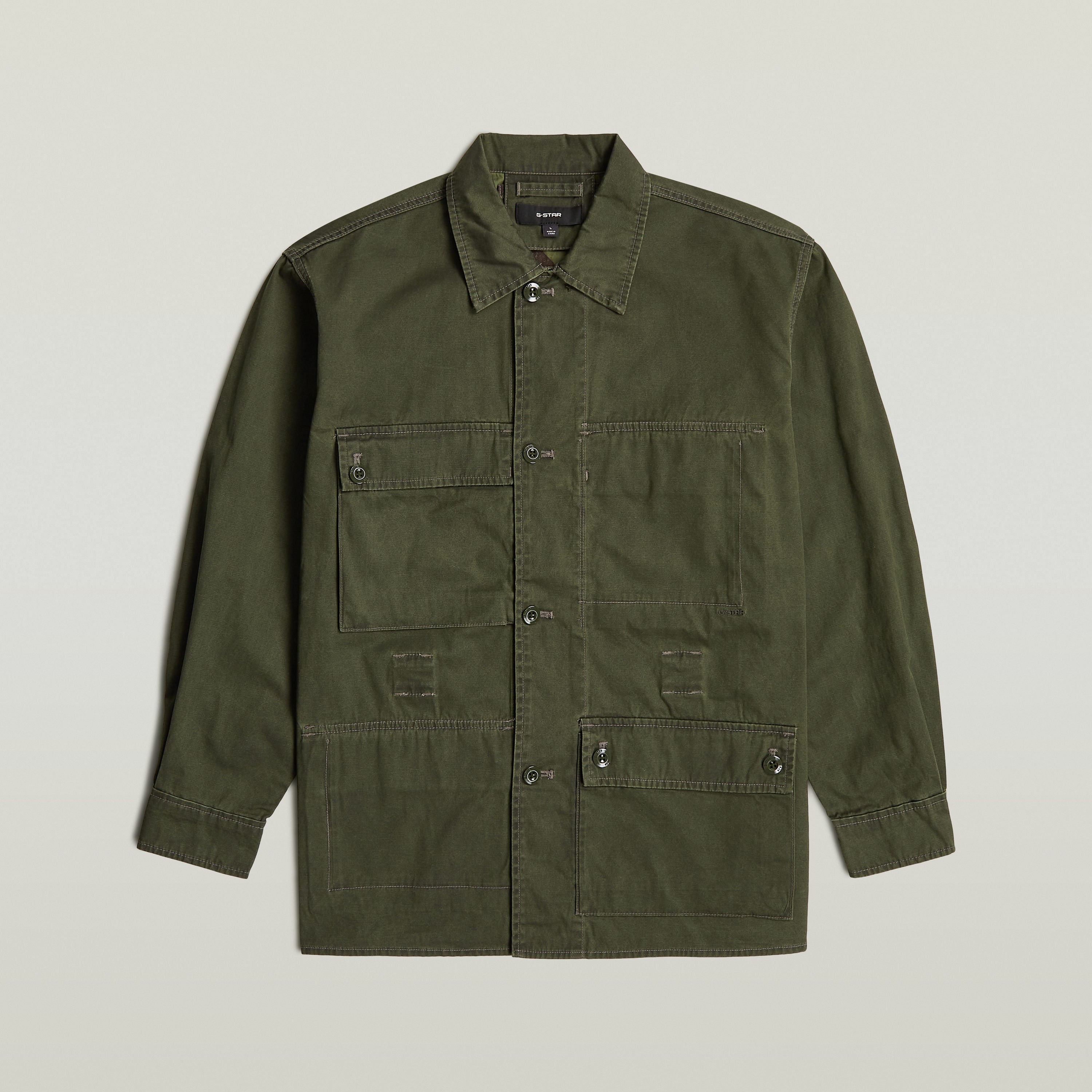 Reversible overshirt for versatile style in olive green with button closure and multiple pockets, made of 100% cotton.