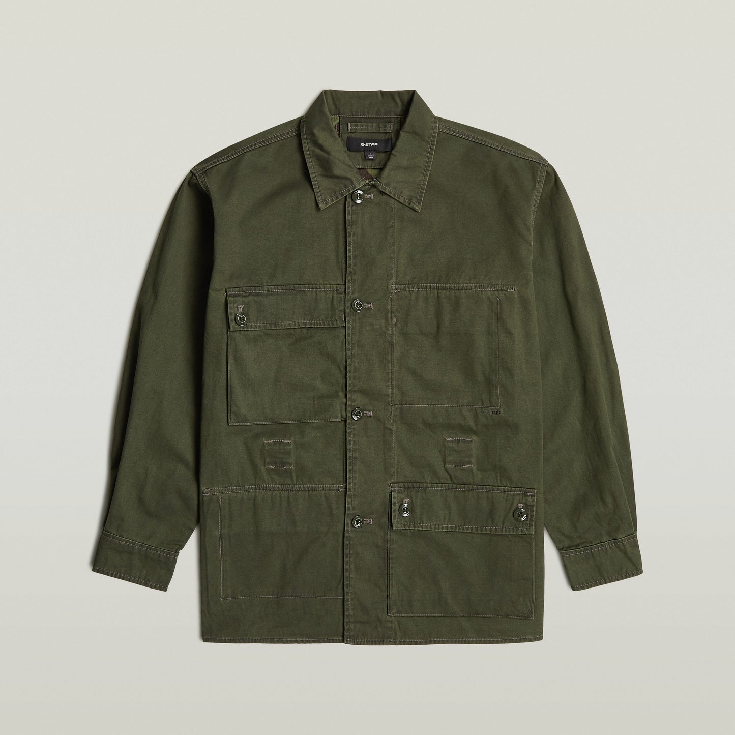 Reversible overshirt for versatile style in olive green with button closure and multiple pockets, made of 100% cotton.