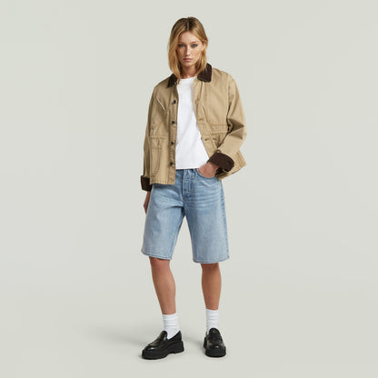 Mujer usando Bermuda Short Clean Edge con chaqueta beige y camiseta blanca, combinados con zapatos negros.