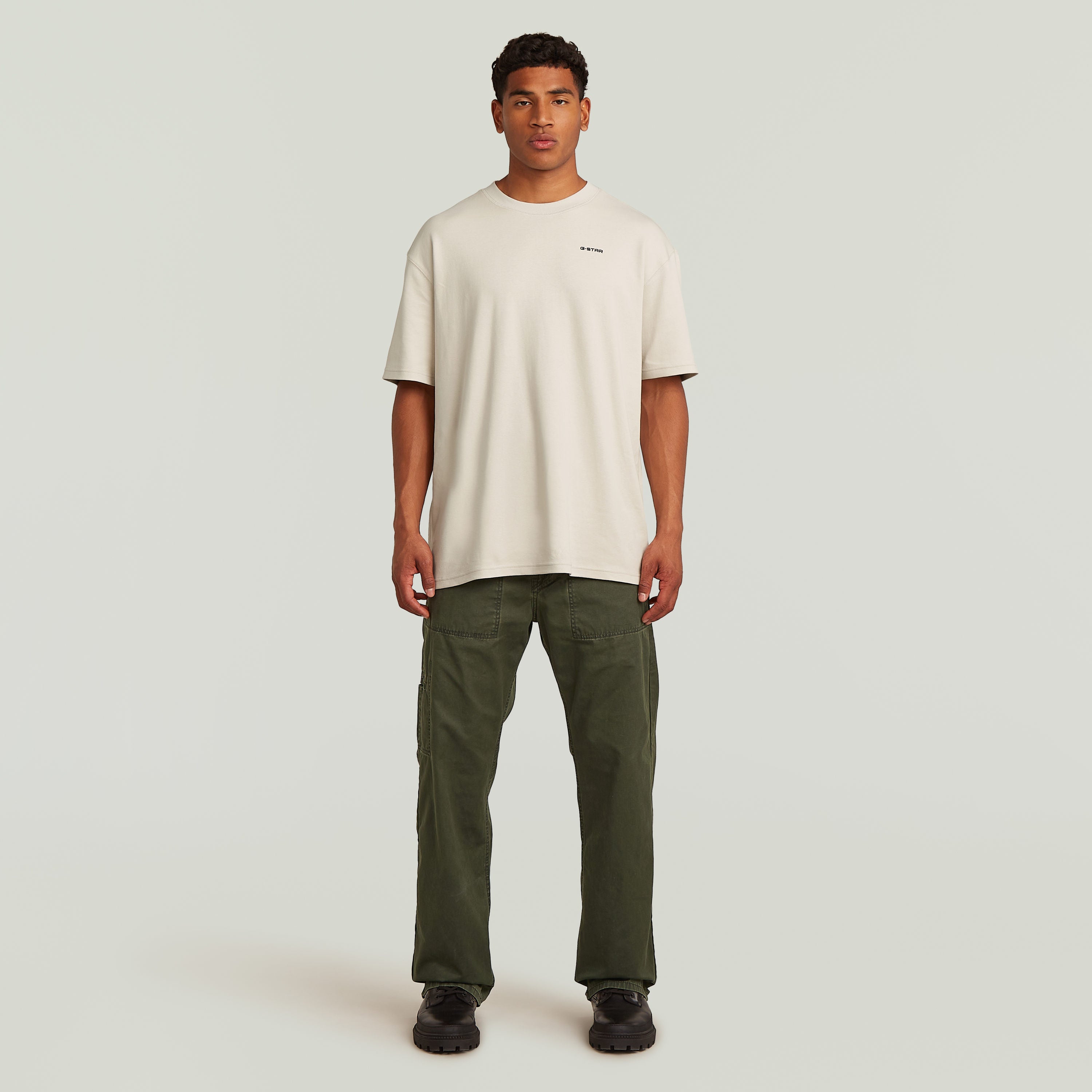 Modelo masculino vistiendo camiseta beige y pantalones chinos reversibles relaxed straight en color verde.