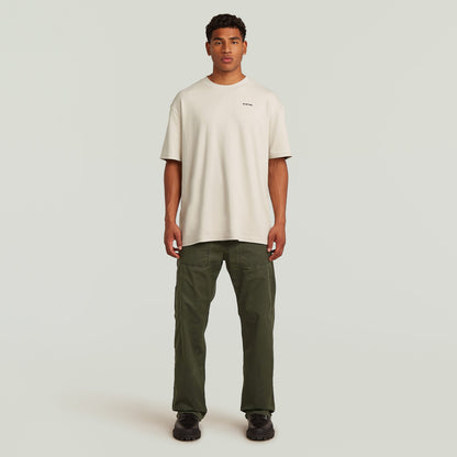 Modelo masculino vistiendo camiseta beige y pantalones chinos reversibles relaxed straight en color verde.