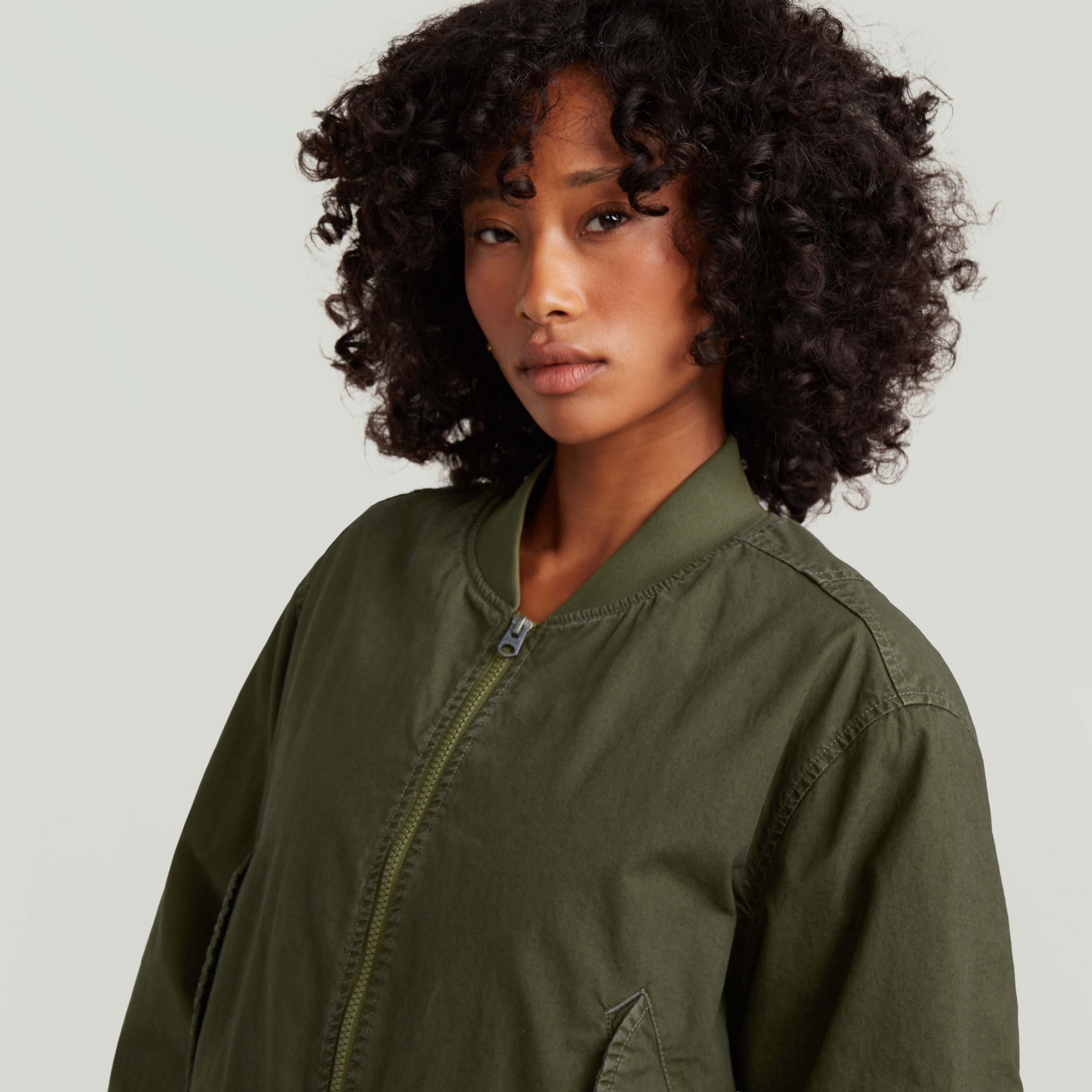 Mujer con chaqueta bomber verde, mostrando el diseño acolchado de la padded bomber jacket.