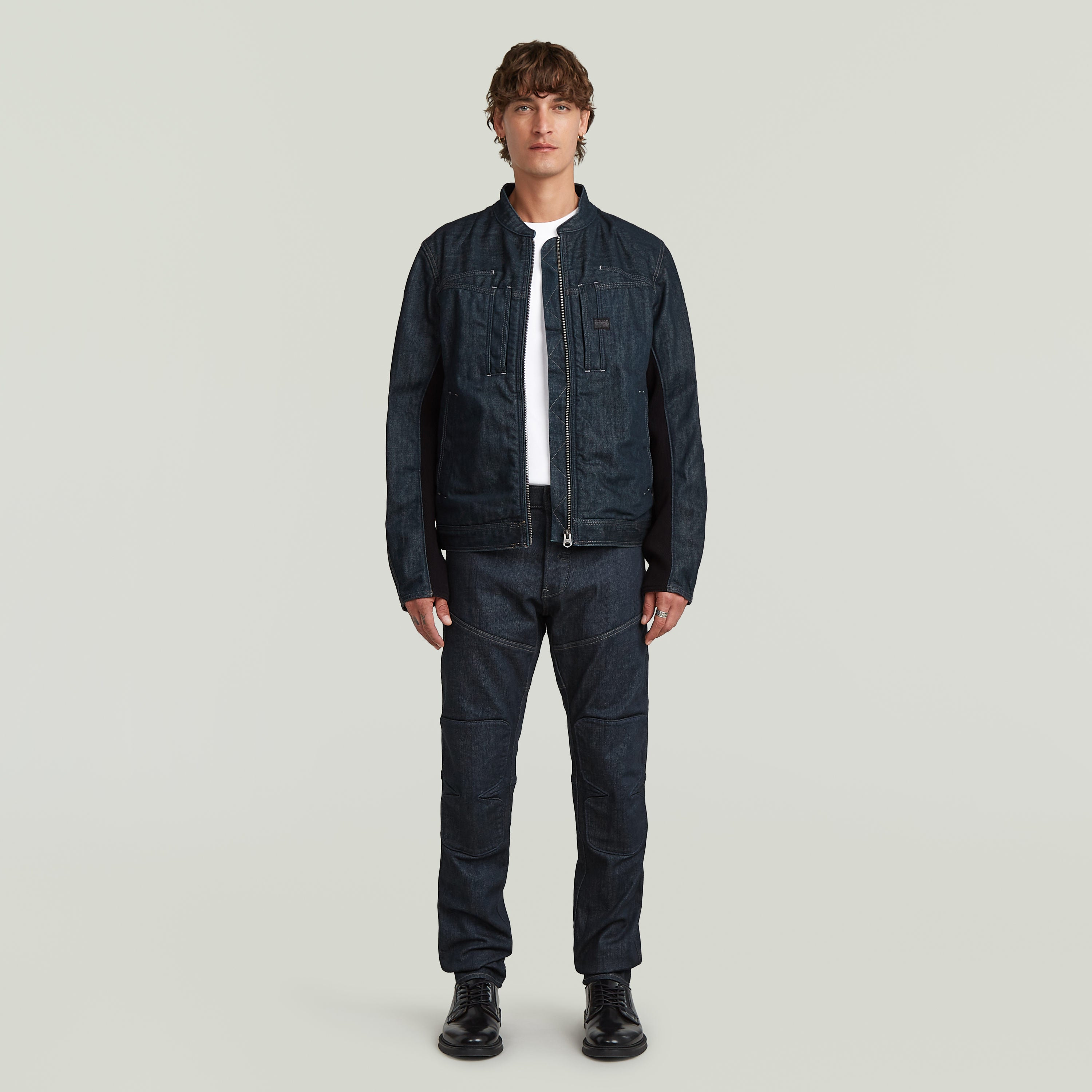 Modelo vistiendo chaqueta biker de diseño minimalista en denim greencast con corte ajustado.