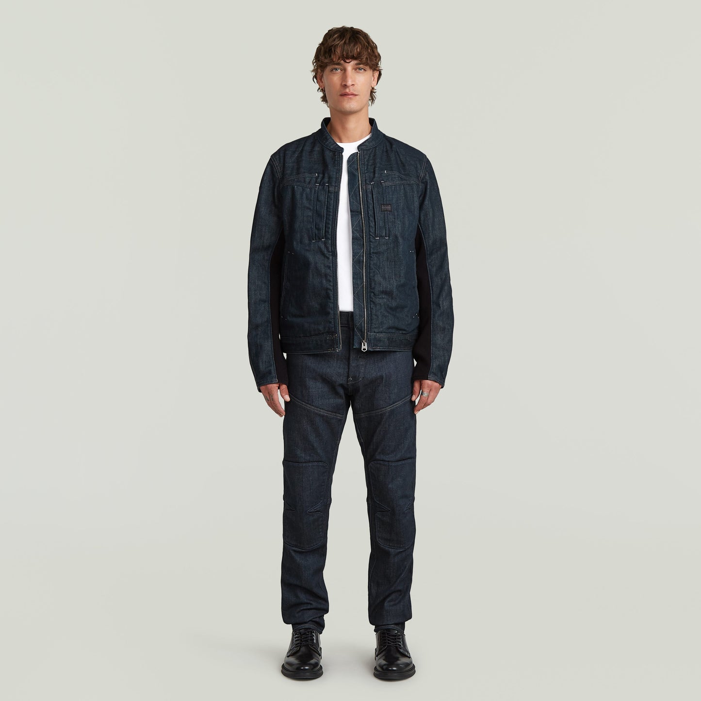 Modelo vistiendo chaqueta biker de diseño minimalista en denim greencast con corte ajustado.