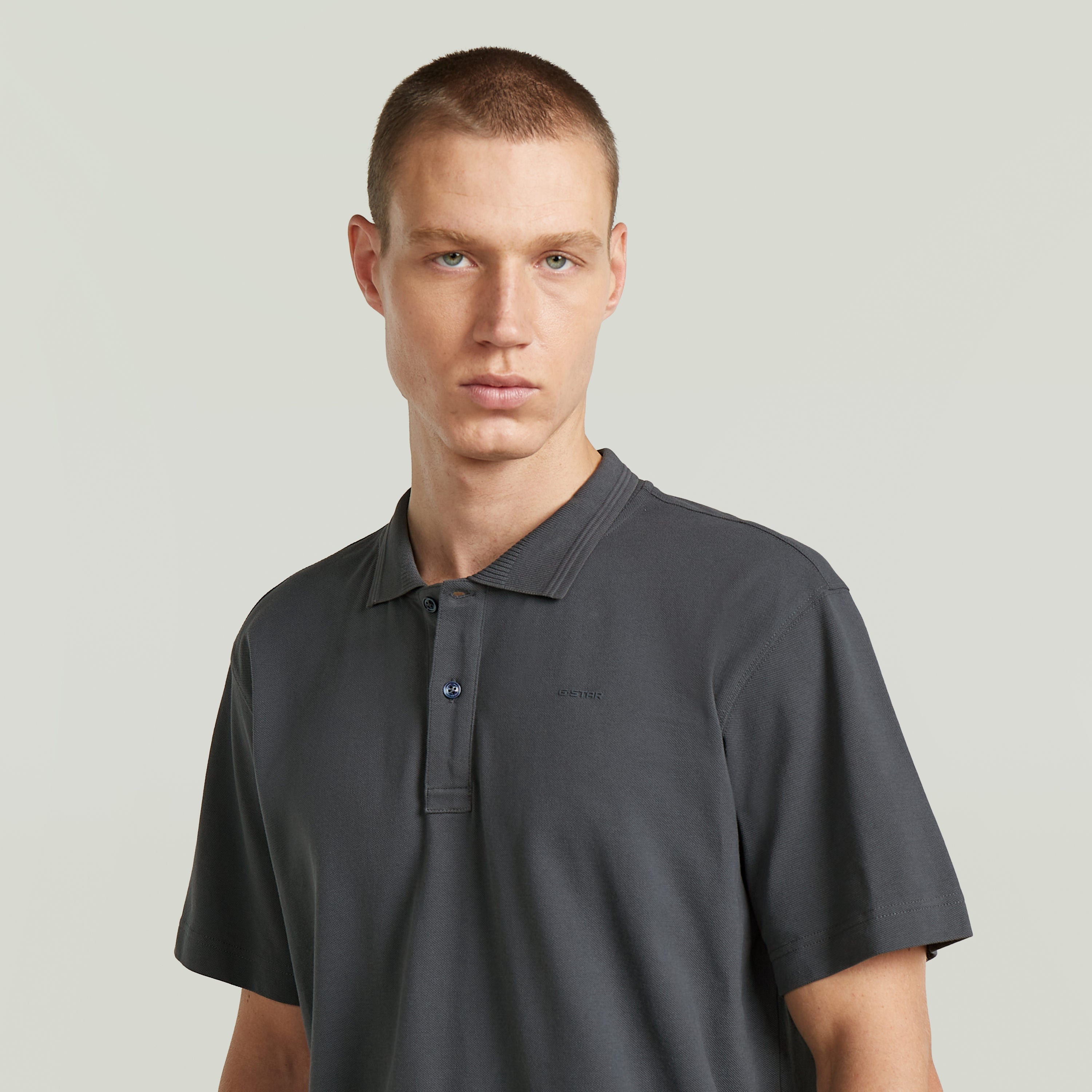 Hombre luciendo la camisa polo core regular shirt en color gris con cuello y cierre de botones.
