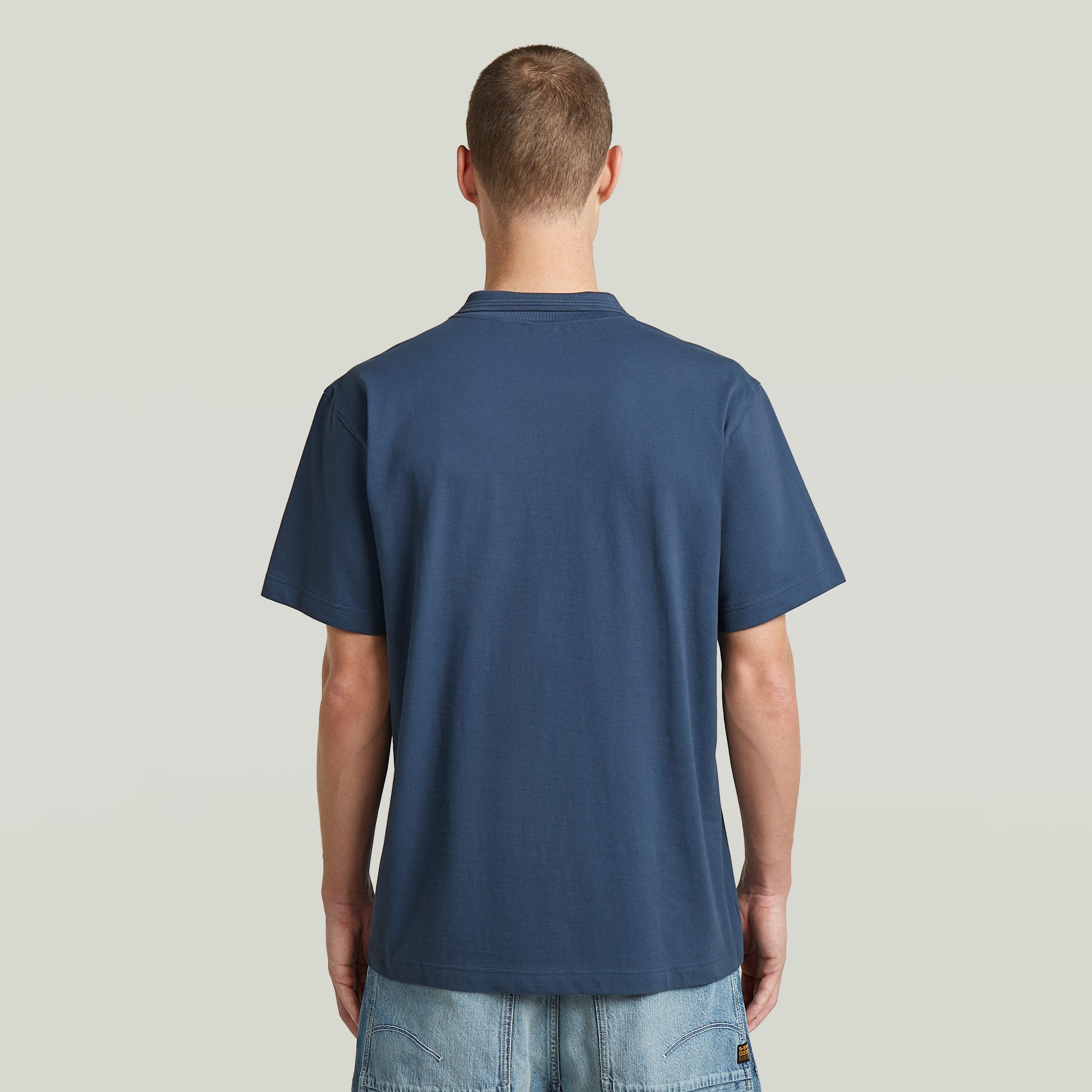 Rear view of a man wearing the polo core regular shirt in intermediate blue, showcasing its comfortable fit.