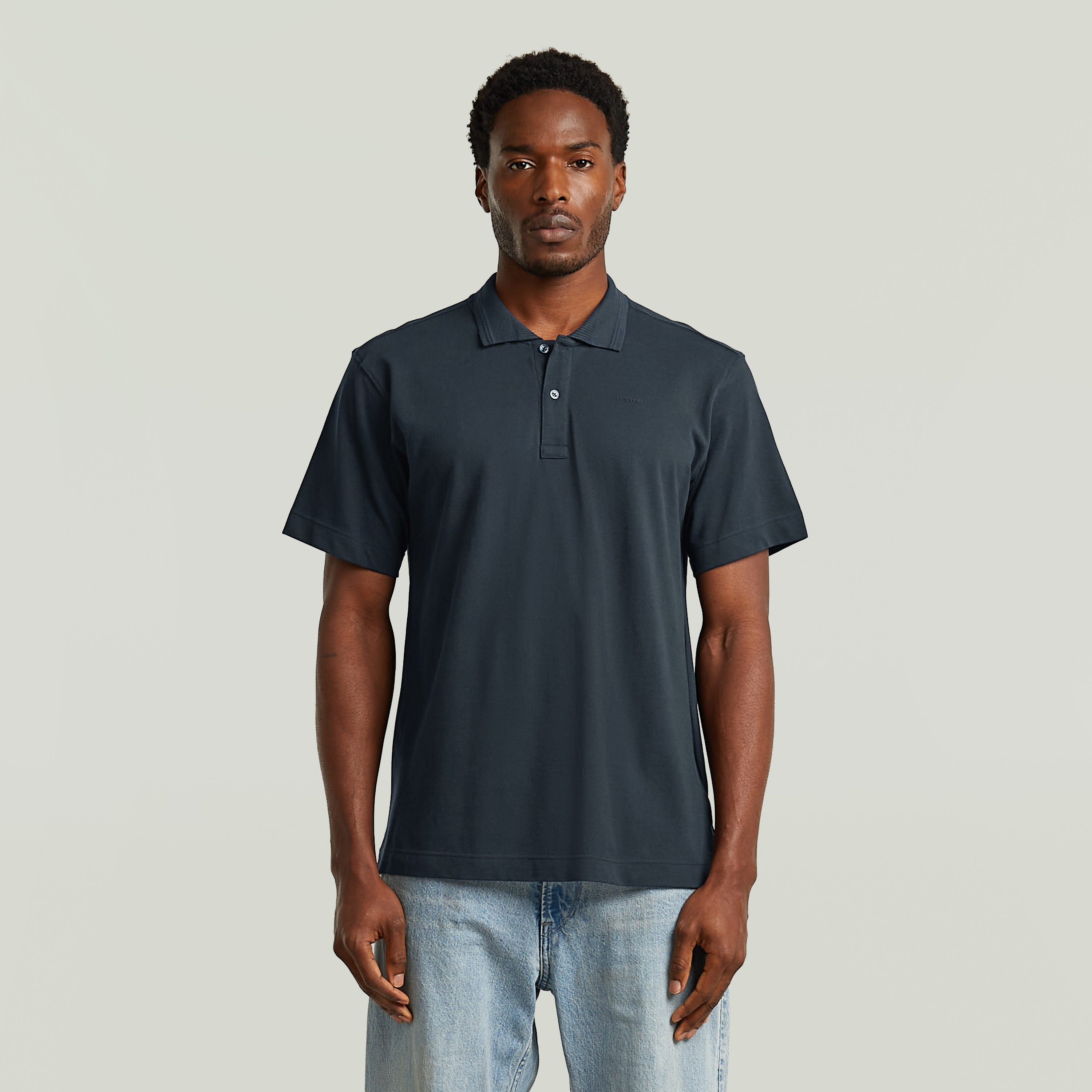 Modelo masculino vistiendo una eco-friendly polo shirt de color azul oscuro con cuello clásico y cierre de botones.