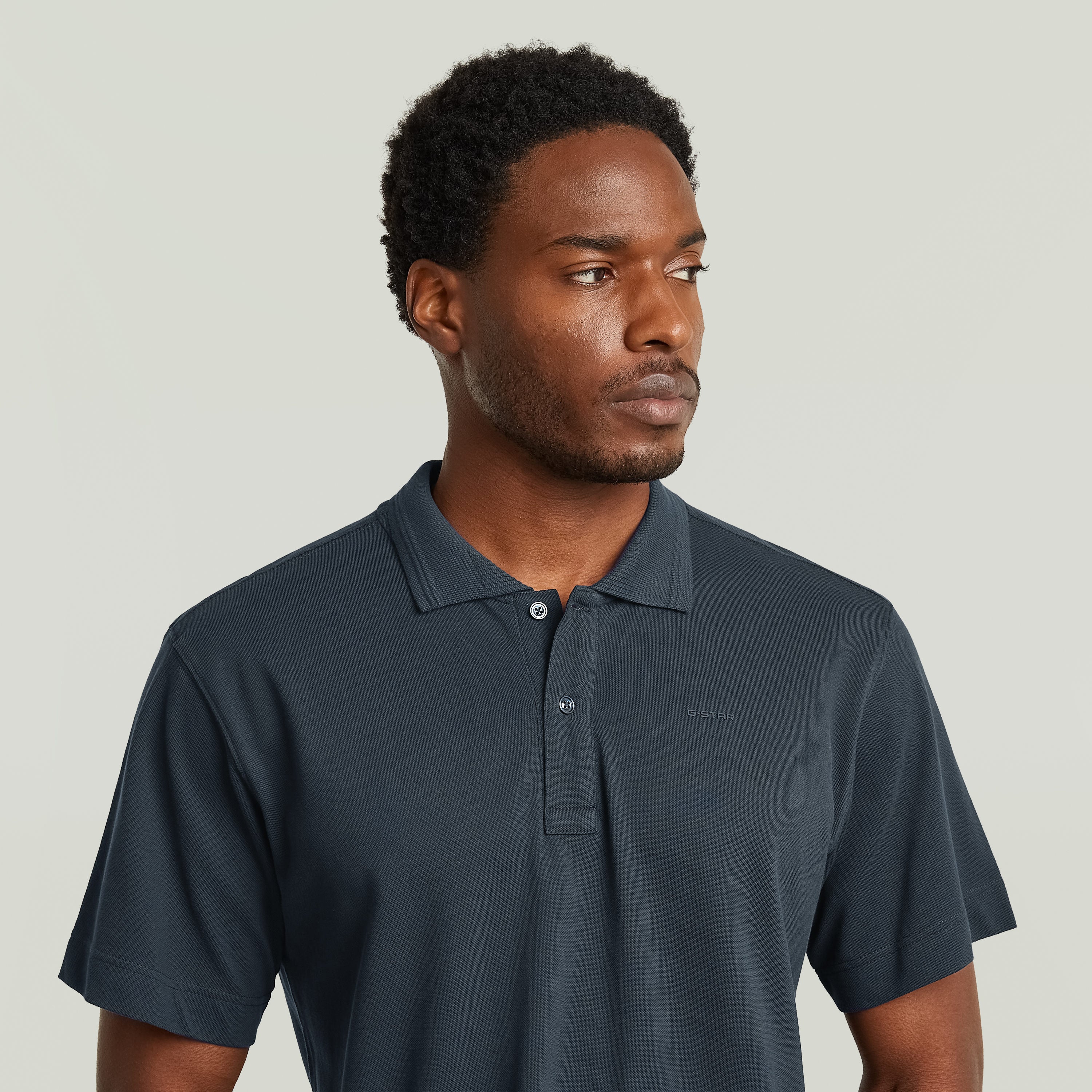Modelo luciendo un polo eco-friendly polo shirt en color azul oscuro con cuello clásico y cierre de botones.