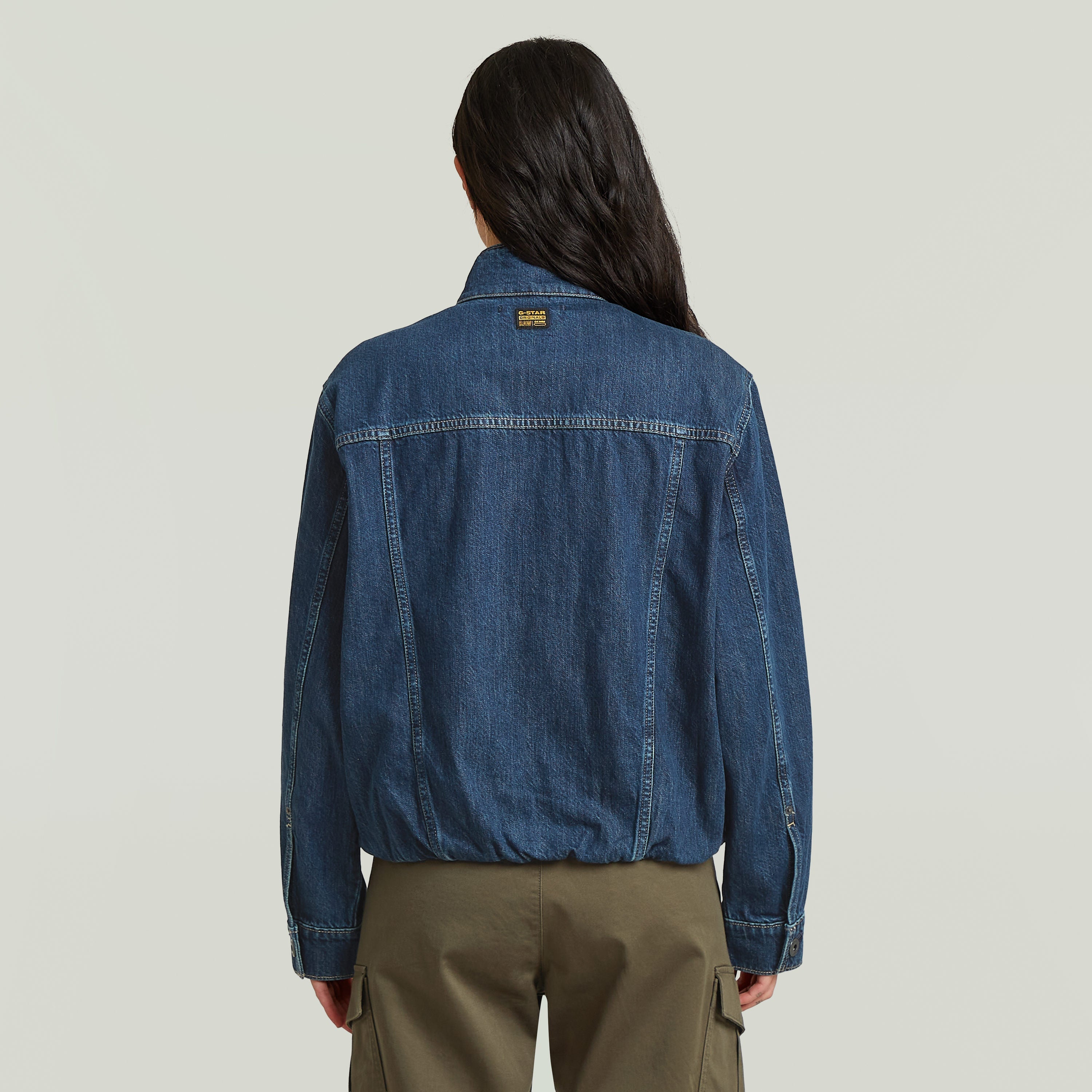 Mujer usando chaqueta Rib Trucker mostrando el diseño atrás, destacando la sustainable oversized trucker jacket.