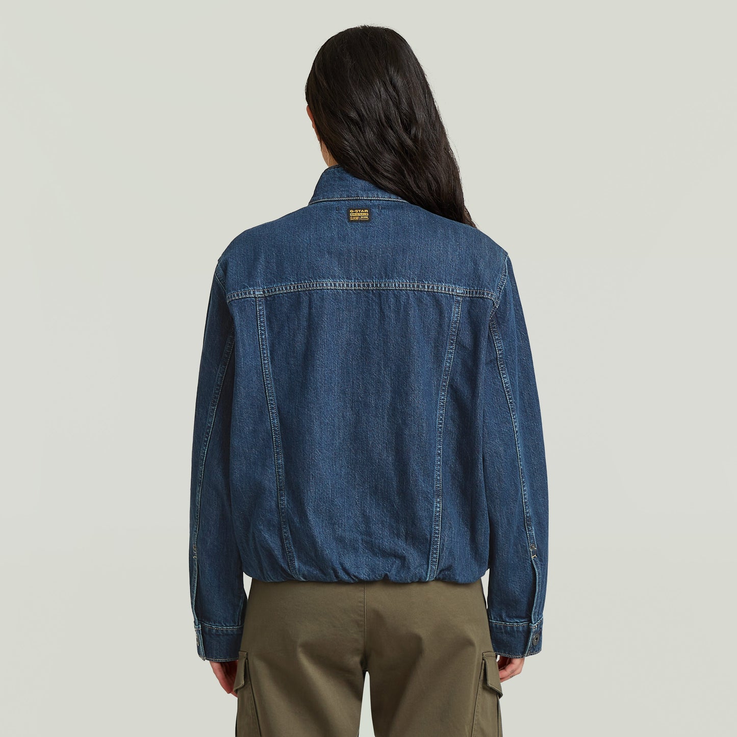 Mujer usando chaqueta Rib Trucker mostrando el diseño atrás, destacando la sustainable oversized trucker jacket.