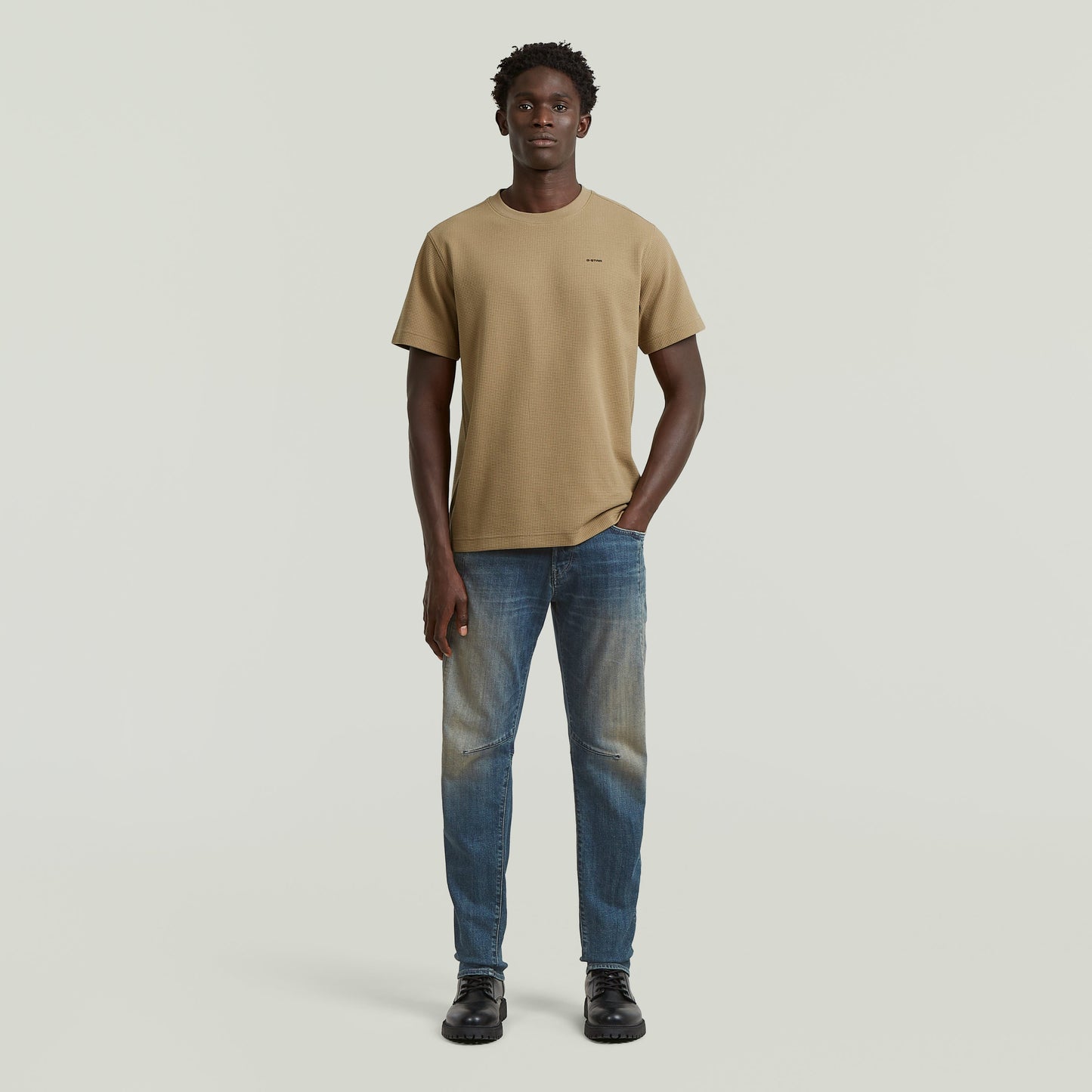 Model wearing a regular fit waffle t-shirt in beige with jeans on a neutral background.