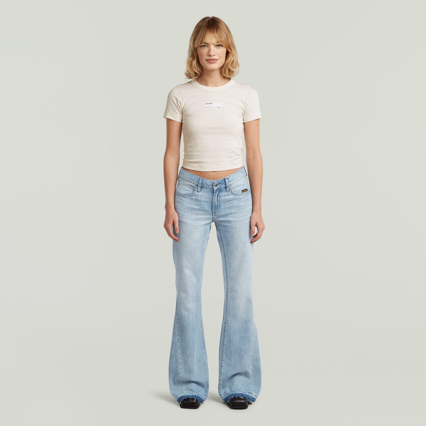 Mujer luciendo jeans Stevey 3D Flare, estilo bootcut en color azul intermedio, 100% algodón.