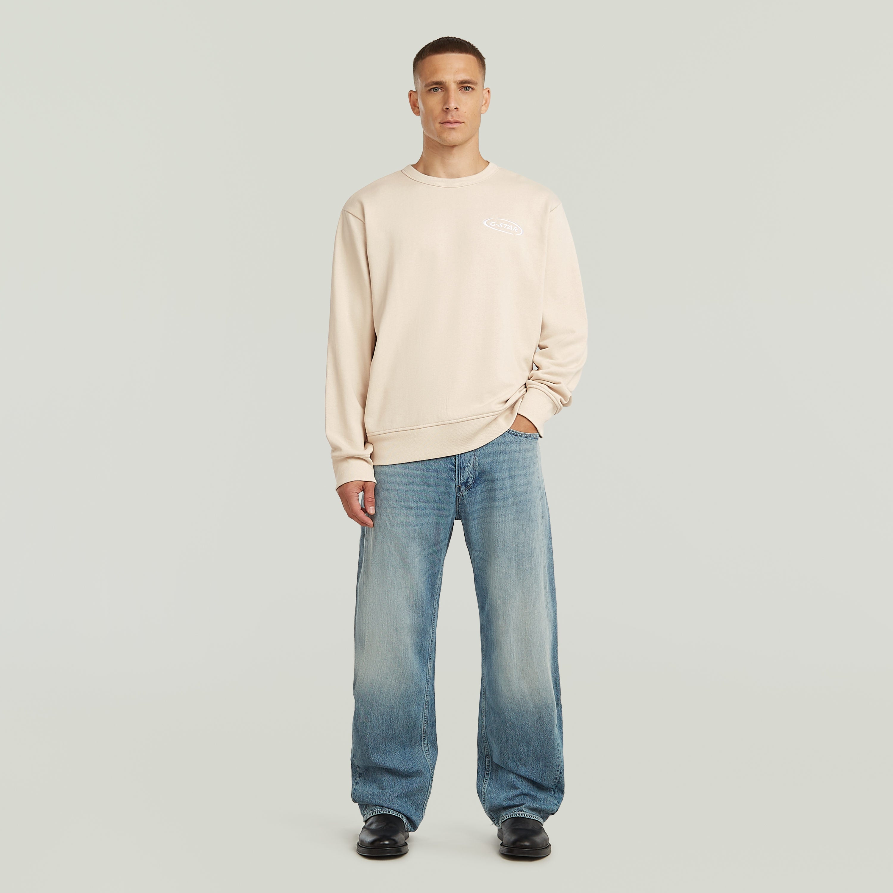 Moda masculina con sudadera con logotipo de los 90 y jeans anchos, estilo casual y cómodo.