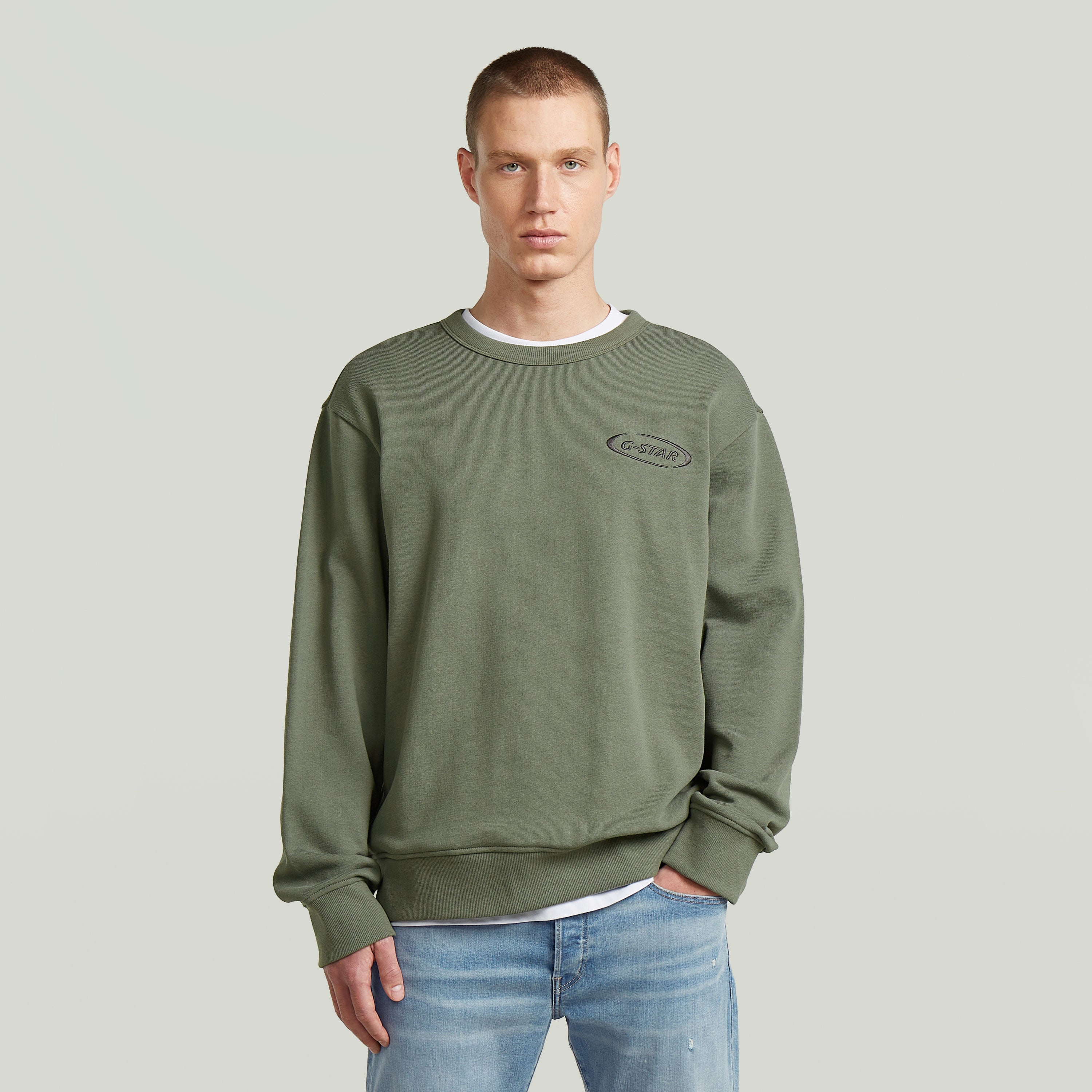 Hombre vistiendo sudadera con logotipo de los 90 en color verde, estilo casual y corte regular.