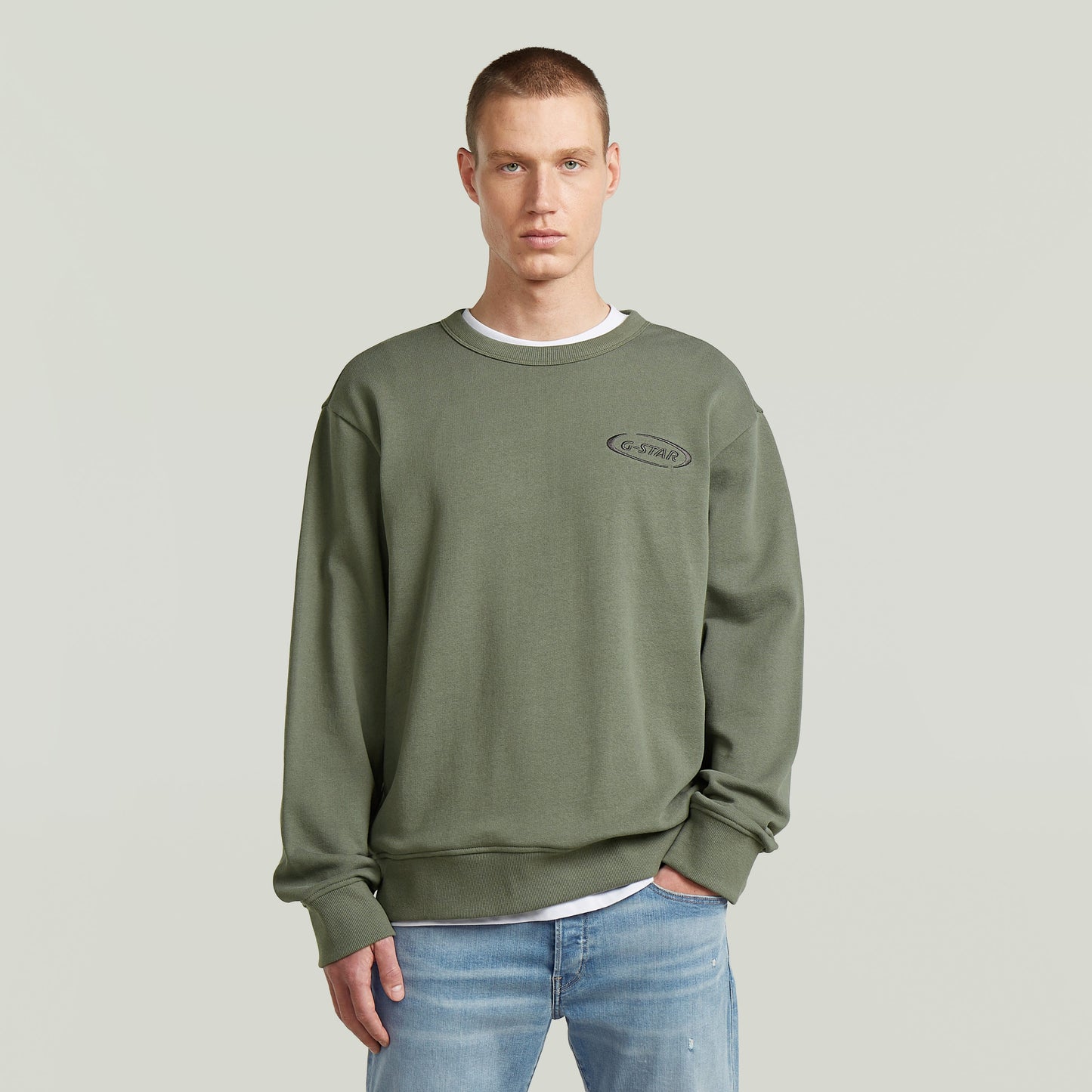 Hombre vistiendo sudadera con logotipo de los 90 en color verde, estilo casual y corte regular.