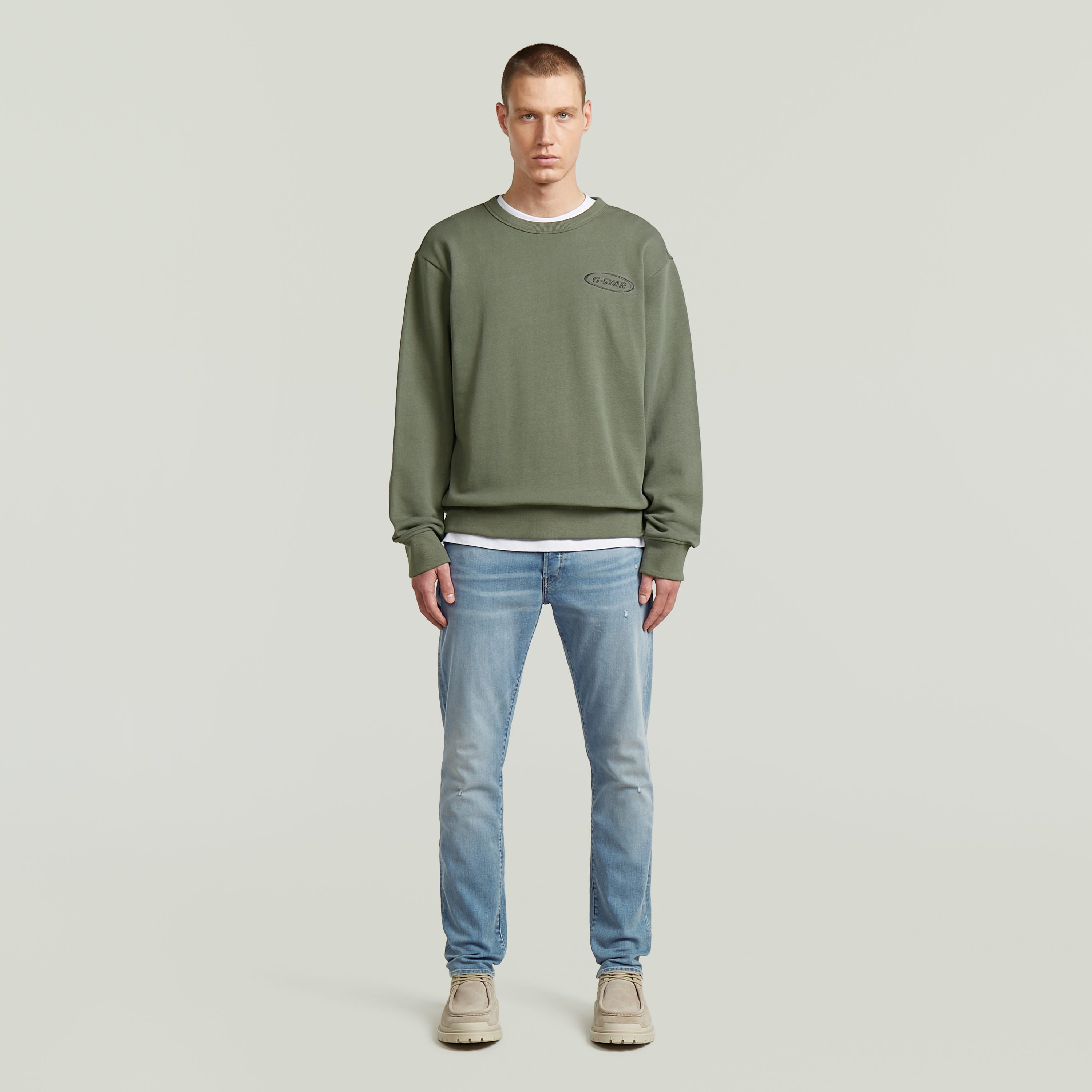 Modelo luciendo sudadera con logotipo de los 90 en color verde, con cuello redondo y diseño atemporal.